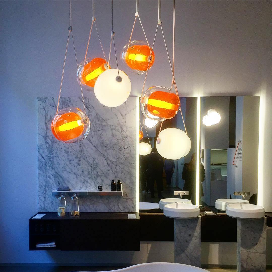 Grouped illuminated glass pendants near a mirror