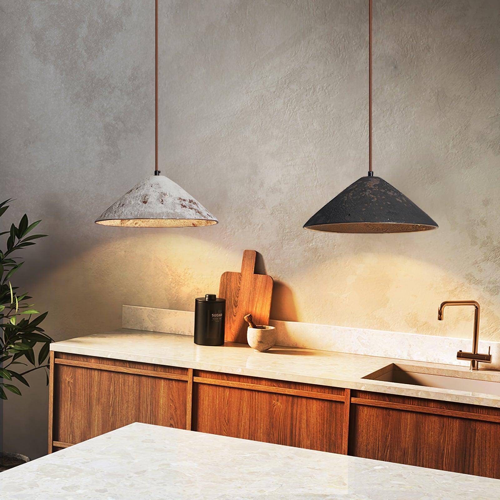 White and black ceramic cone pendants over a kitchen counter with wood cupboards, cutting board, plant and gold-tone faucet