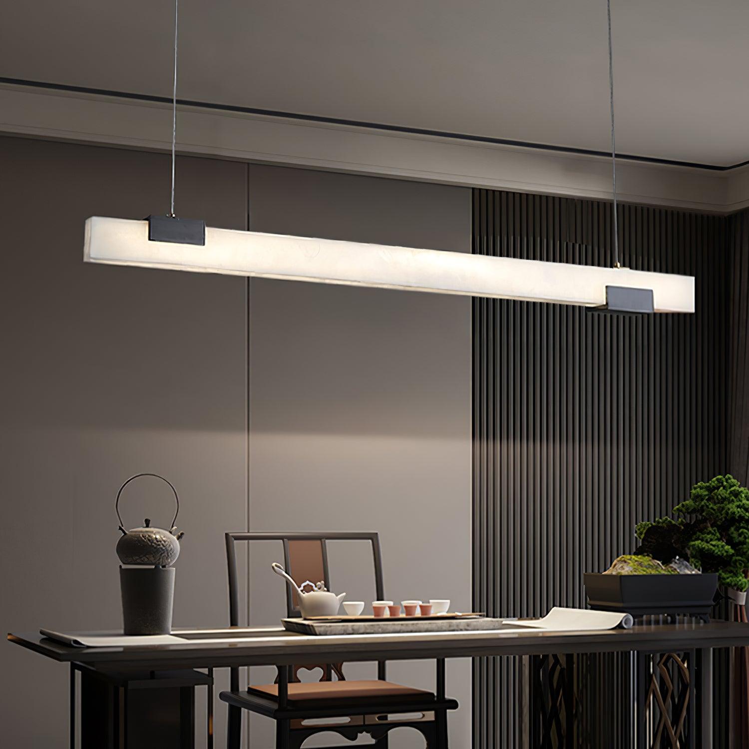 Glowing white pendant bar above a tea table with cups, raised kettle, bonsai and slatted wall