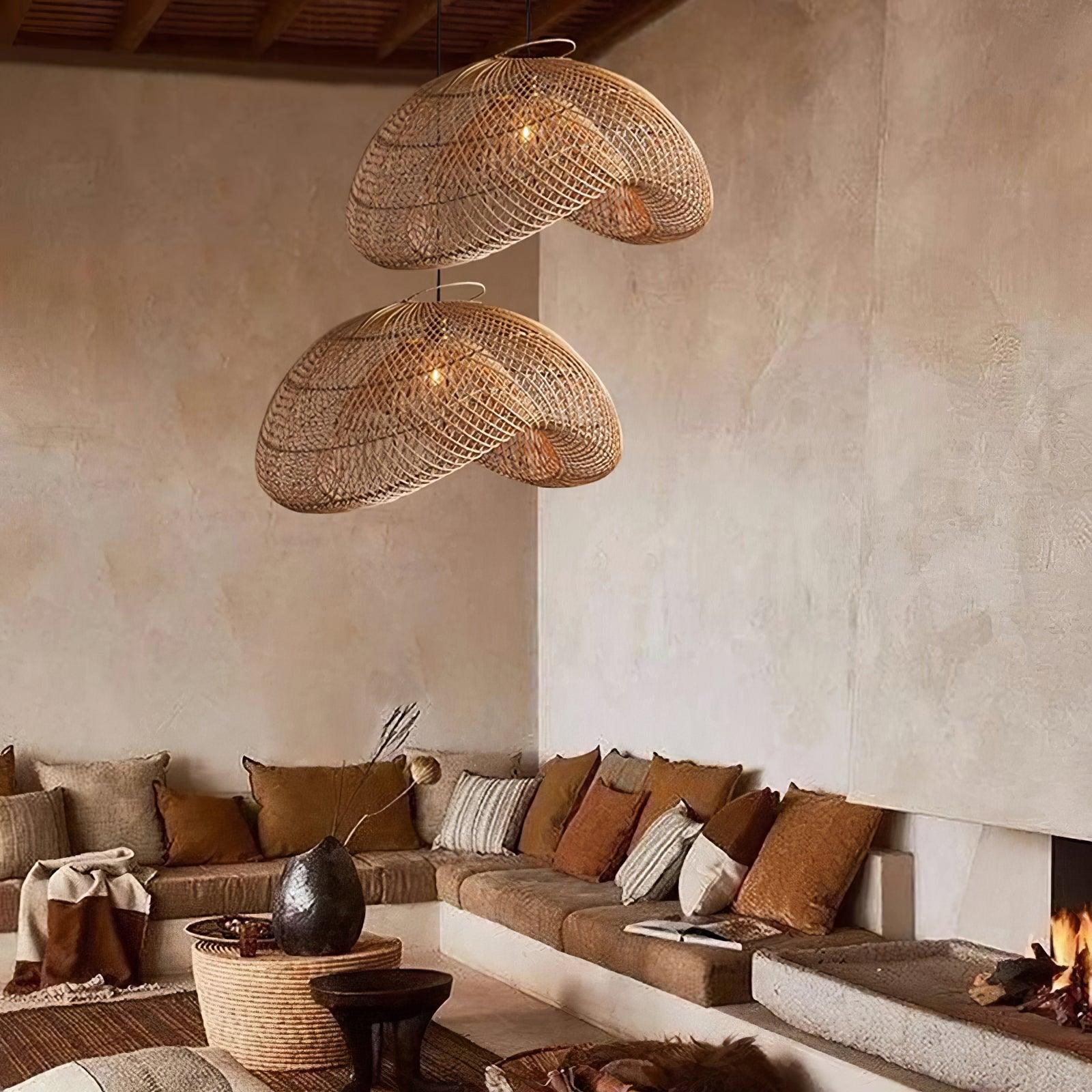 Paired woven pendants over sofa cushions and a round woven table with dark vase beside the fireplace