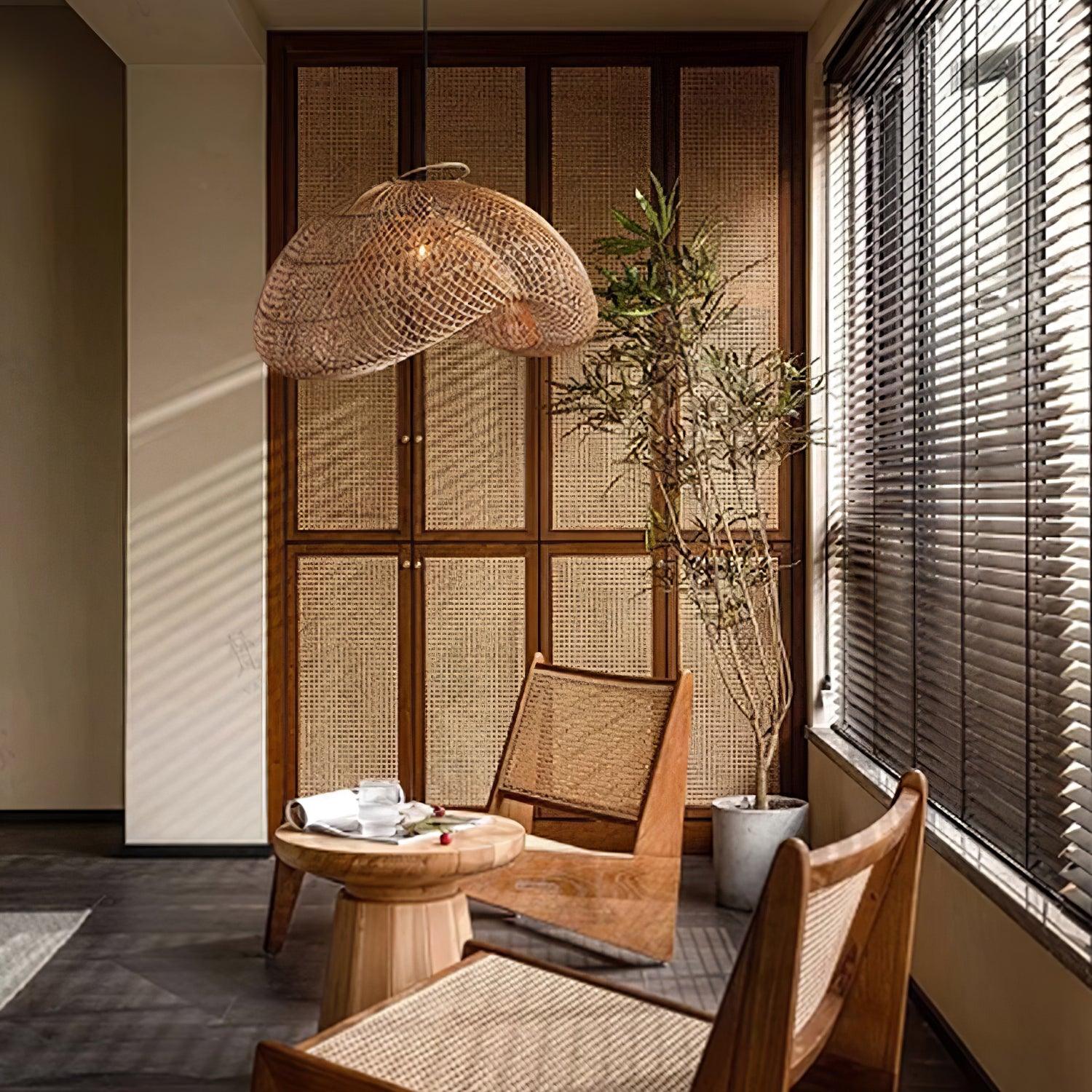Woven wave pendant above a small wooden tea table with cups, woven chairs, wall panels and window blinds