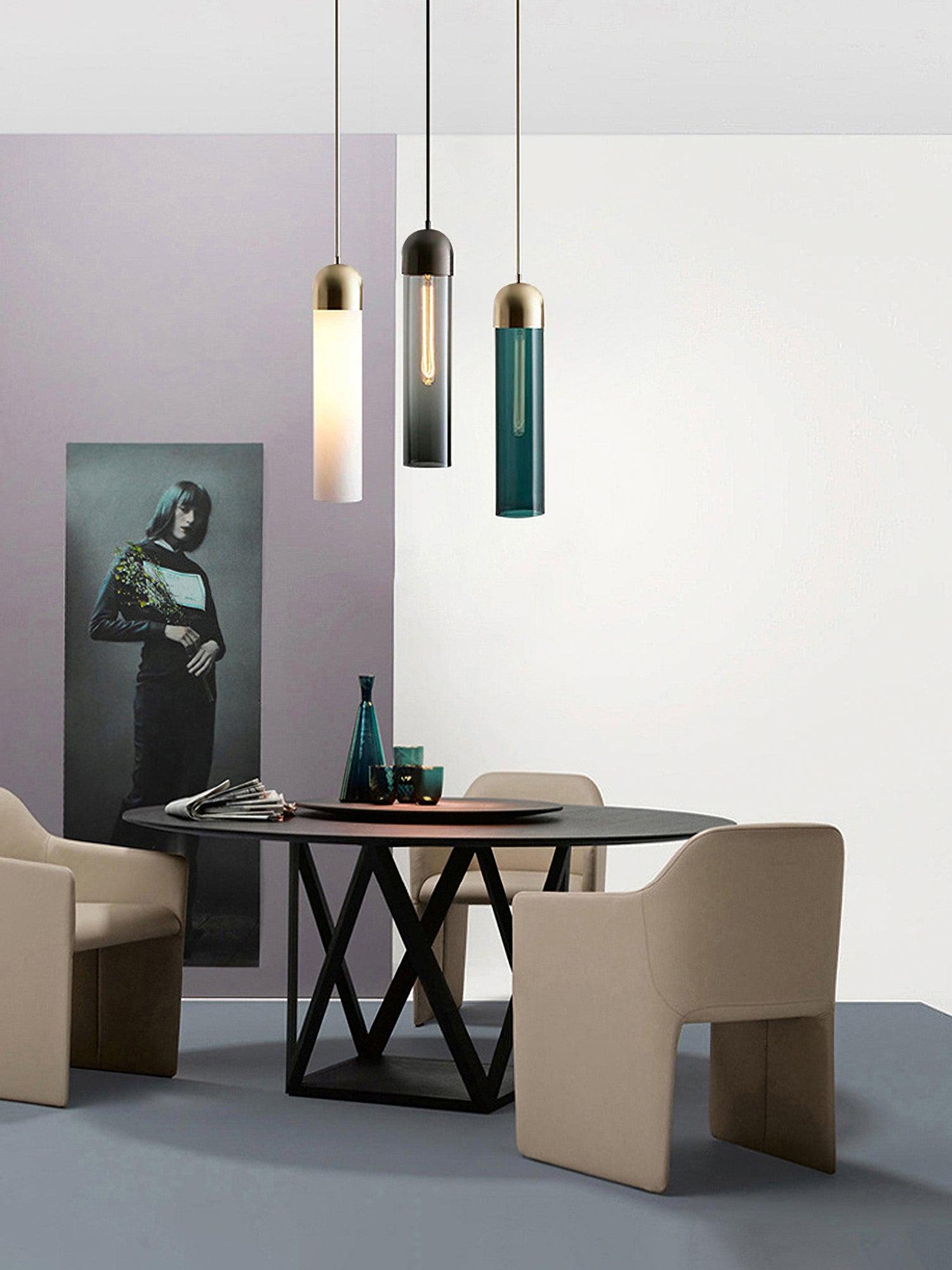 Milk white, smoky and dark green cylinder pendants above a round black dining table
