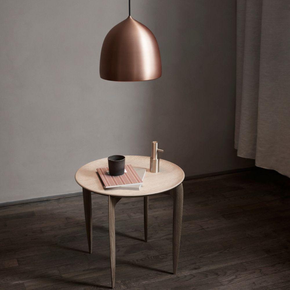 Copper bell pendant above a small round wooden table