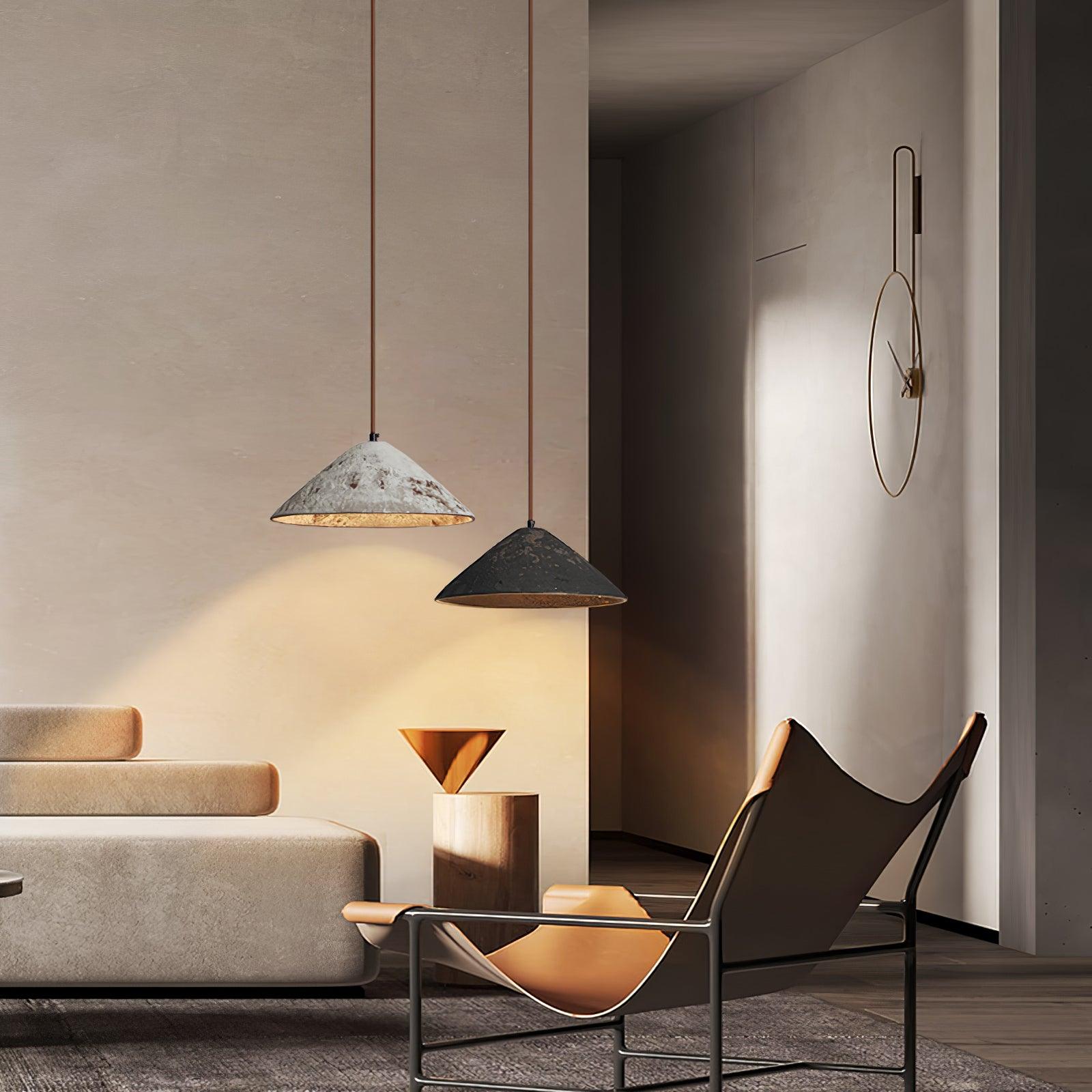 Two white and black cone pendants over a sofa and lounge chair, with a wood pedestal, metallic bowl and large wall clock