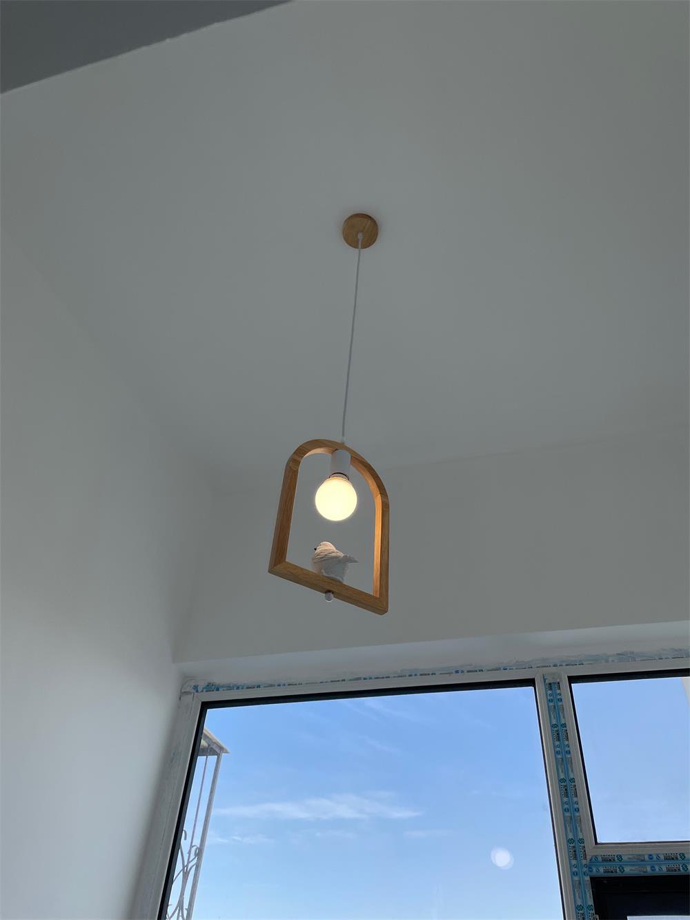 Wooden bird pendant beside a window