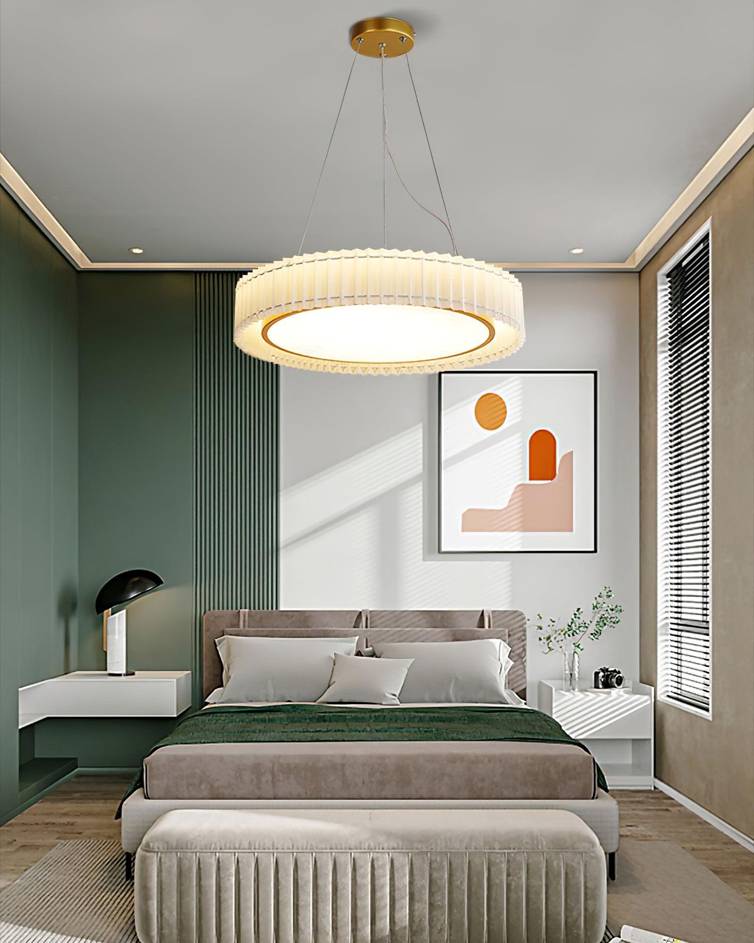 Round pleated pendant above a gray bed with green throw and upholstered bench against gray and green walls