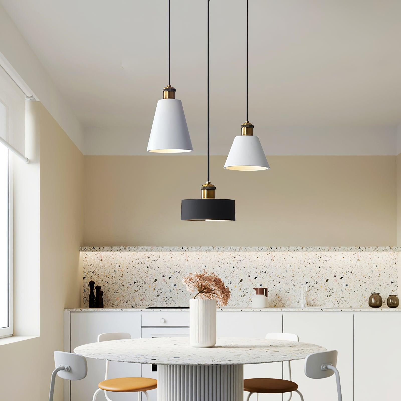 Two white cone shades and a black drum pendant above a bright dining table
