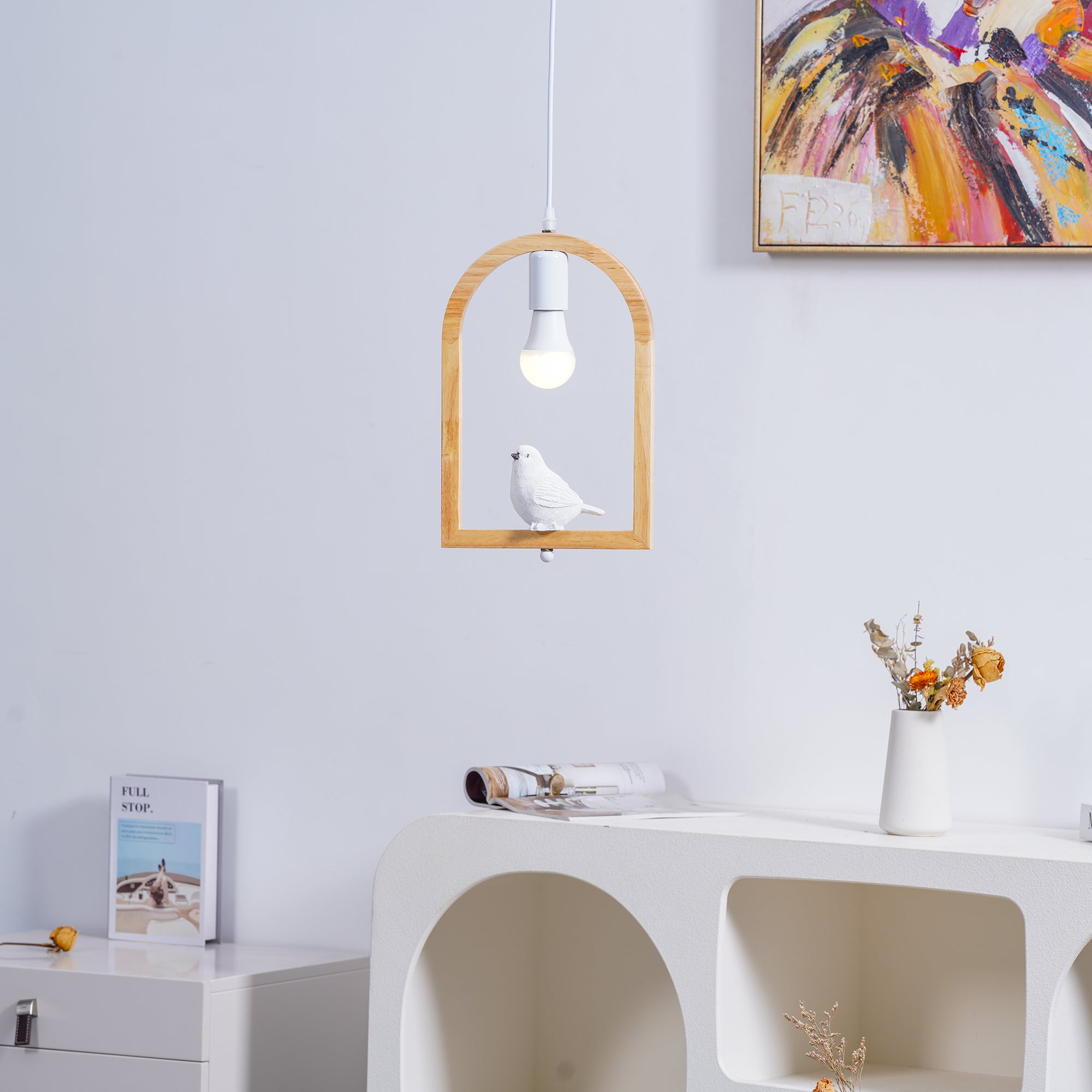 Wooden bird pendant above a white open-shelf console with decorative objects