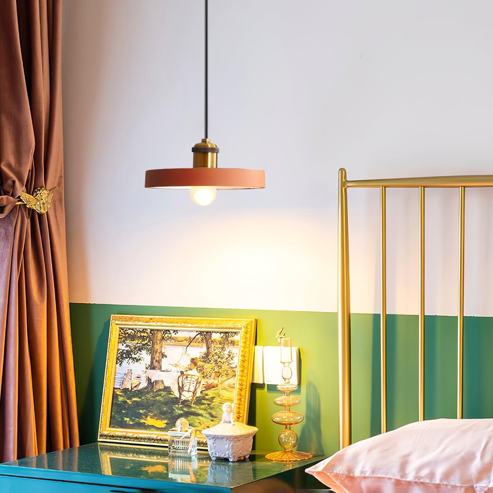 Orange disc pendant above a bedside table