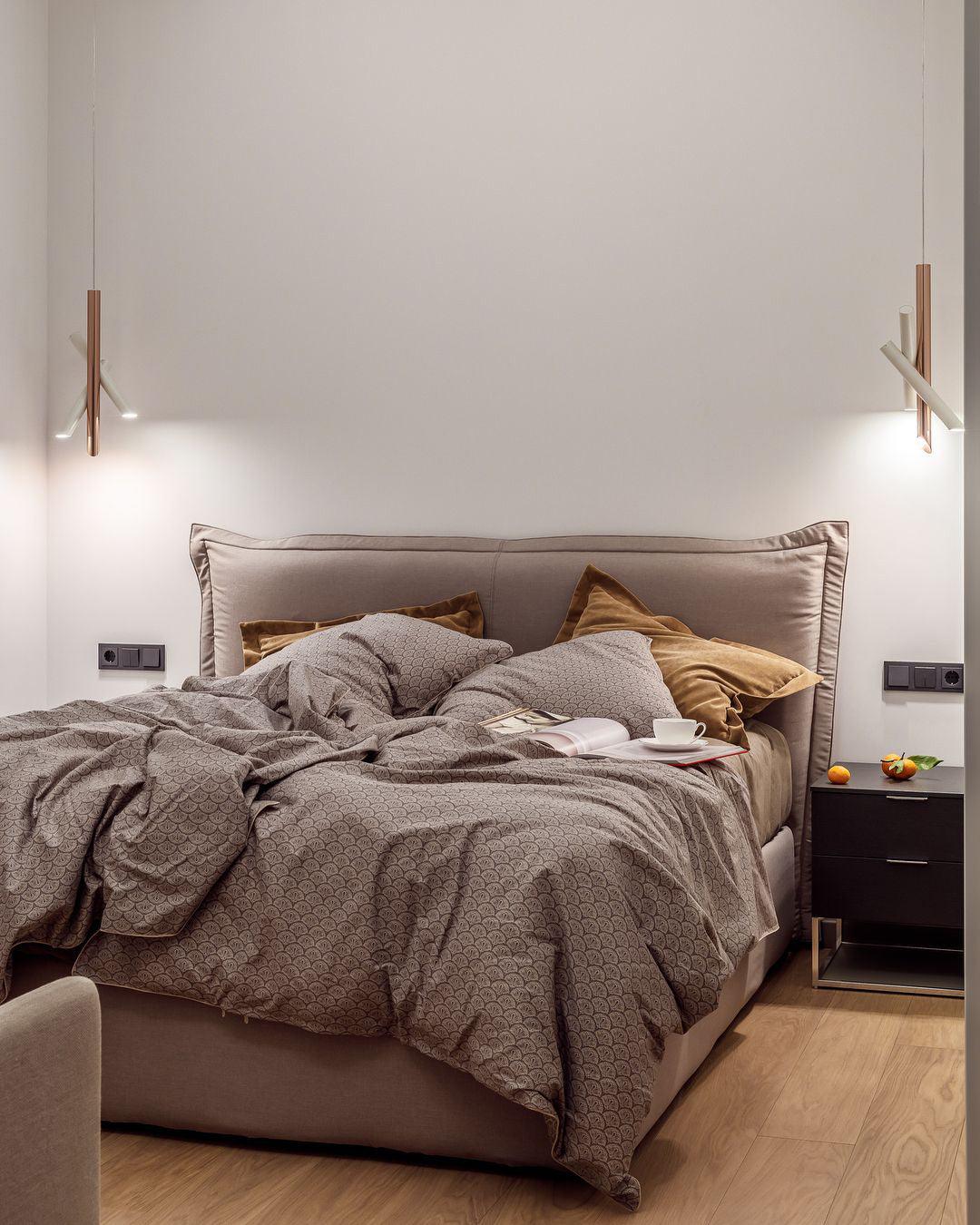 White and rose-gold Tubes pendants on either side of a bed with patterned bedding