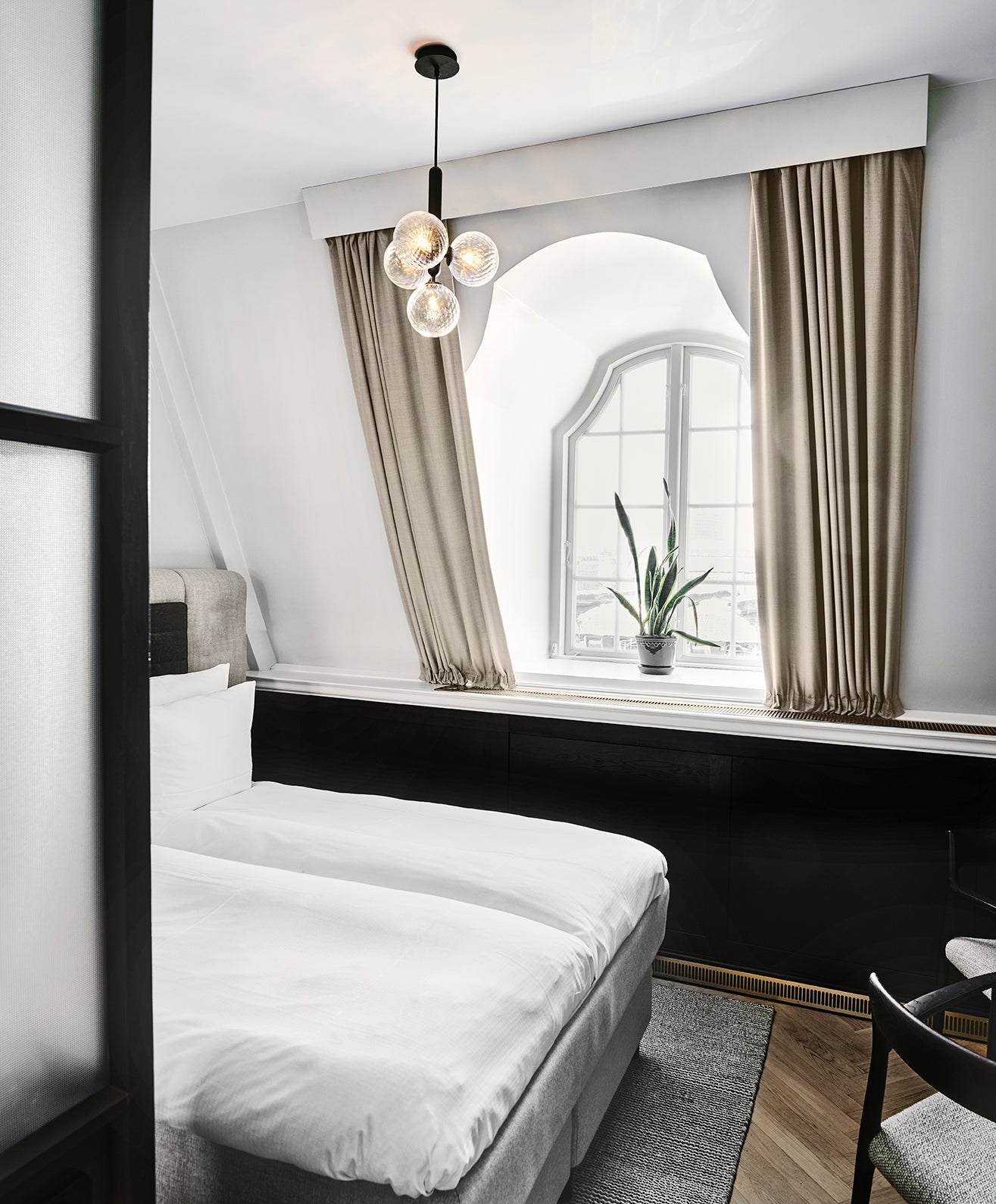 Clear globe pendant above a bed near an arched mirror