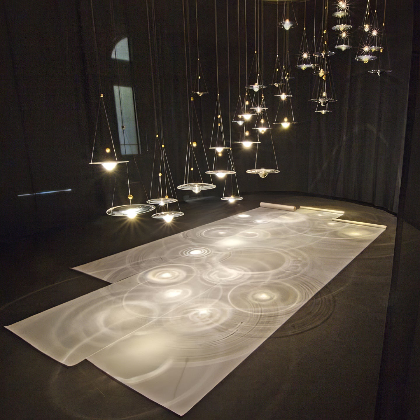Grouped glass pendants casting circular table patterns