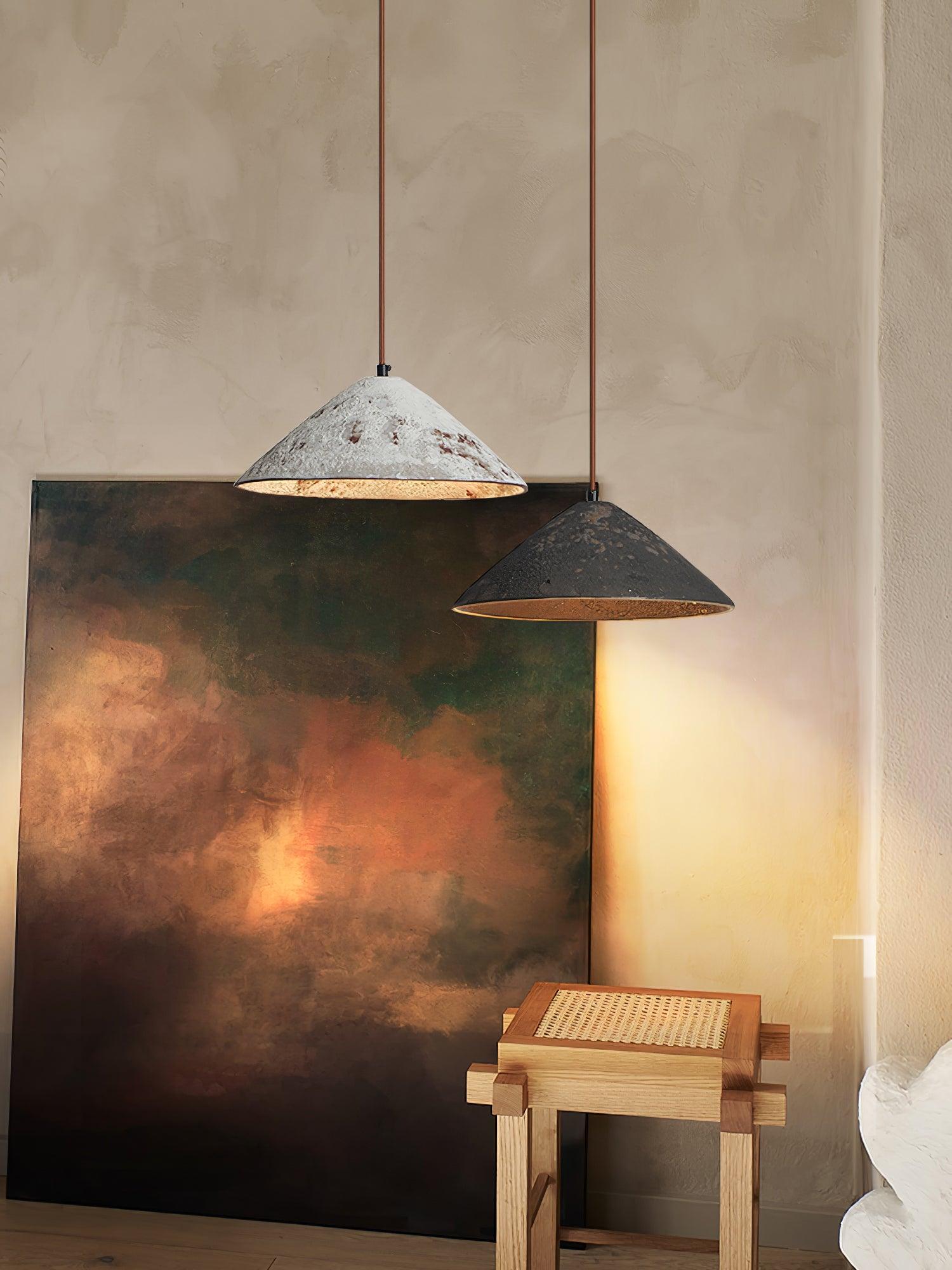 Portrait view of white and black ceramic cones above a woven wooden stool, with abstract art and textured wall behind