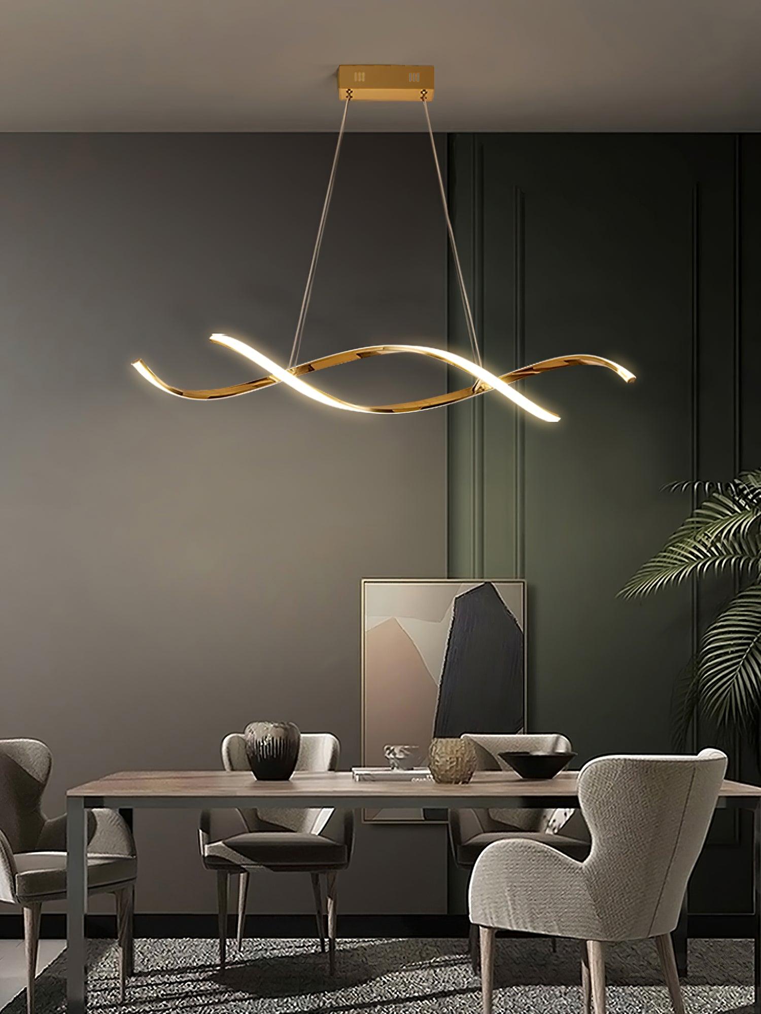 Gold wave pendant above a table with grey chairs beside a green wall and palm