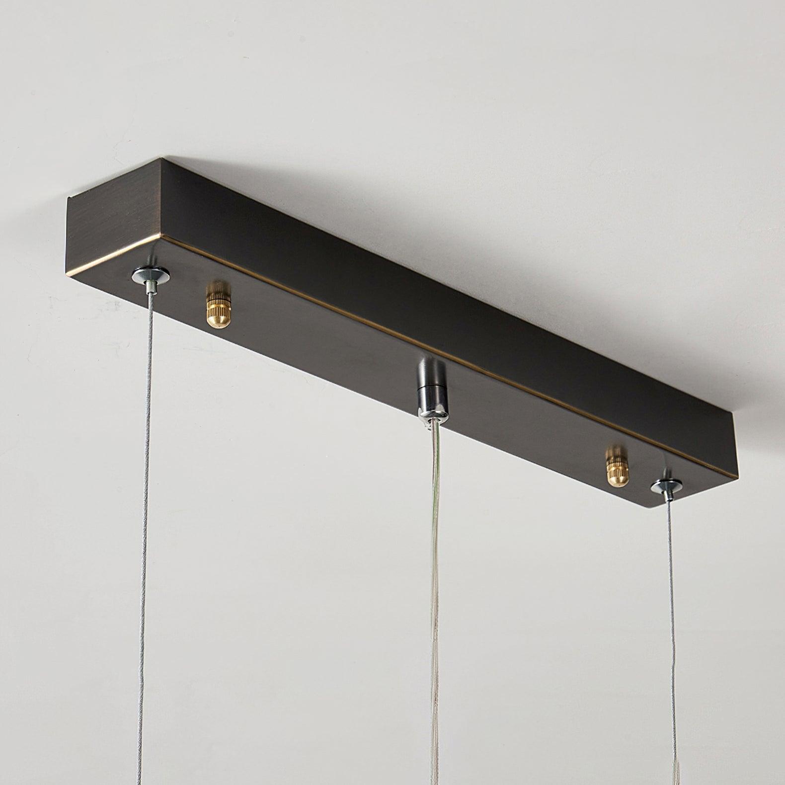 Underside close-up of a black rectangular canopy with outer suspension cables, central wire and gold-tone caps
