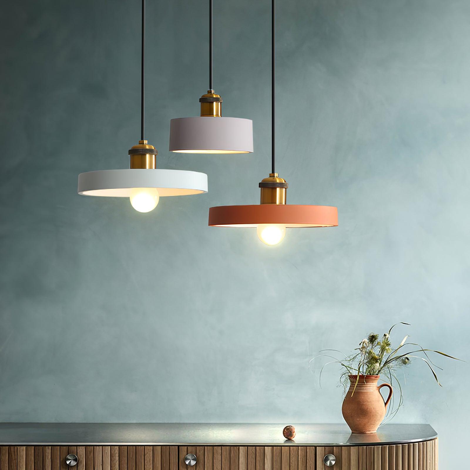 Mixed drum and disc pendants against a teal wall