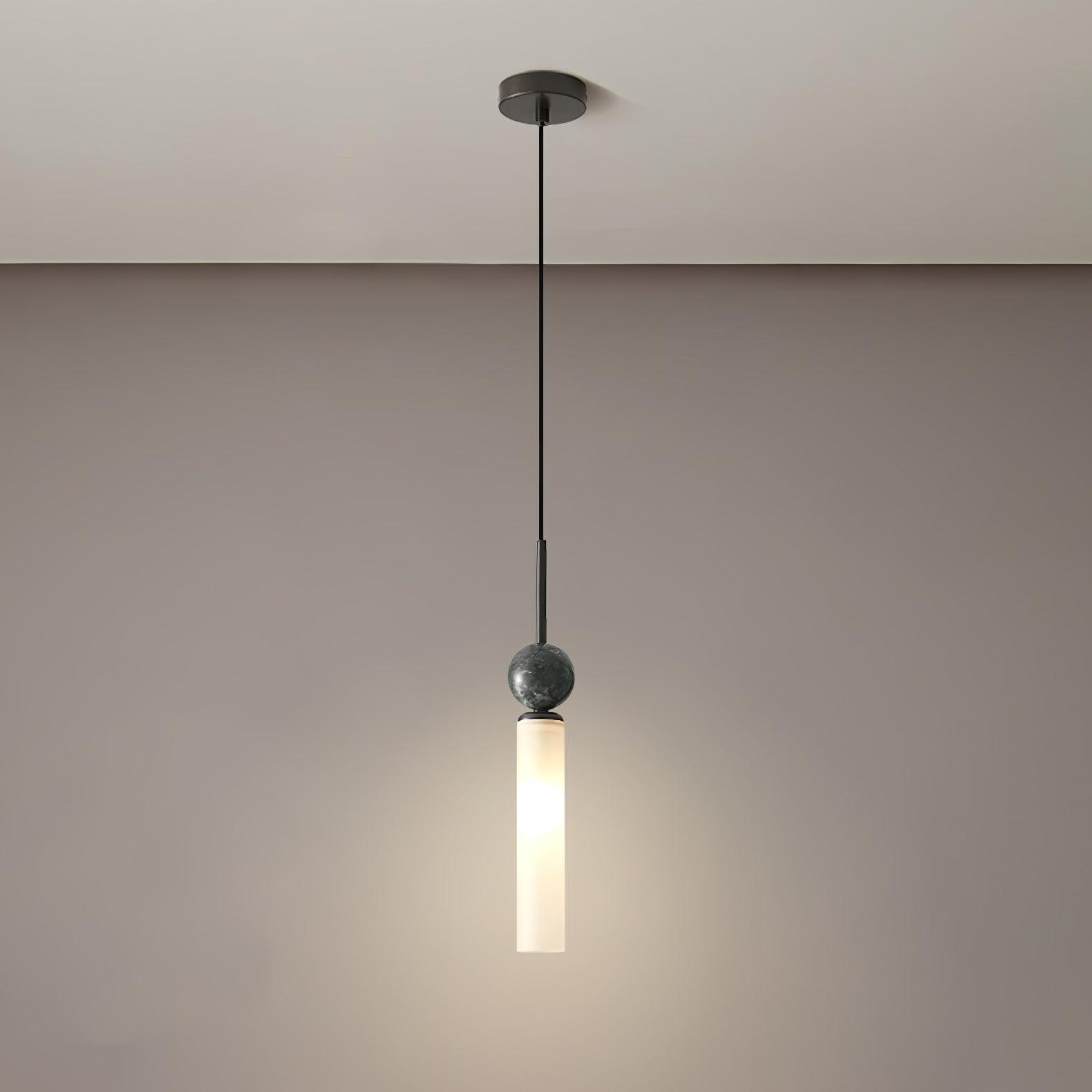 Full black single pendant against warm pale wall, with round canopy, veined sphere and white tube surrounded by light halo