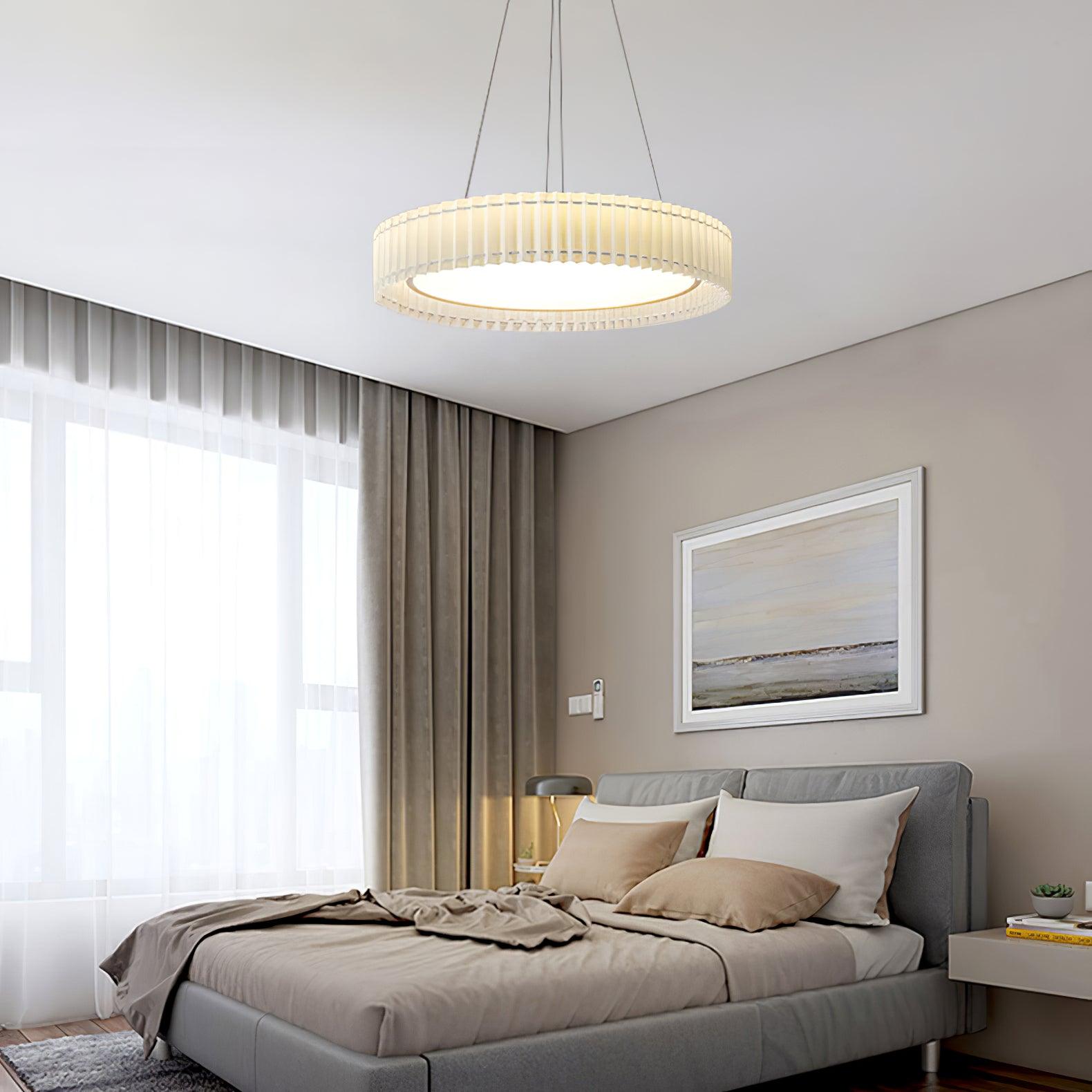 Lit pleated pendant above a gray upholstered bed and landscape artwork beside a broad window