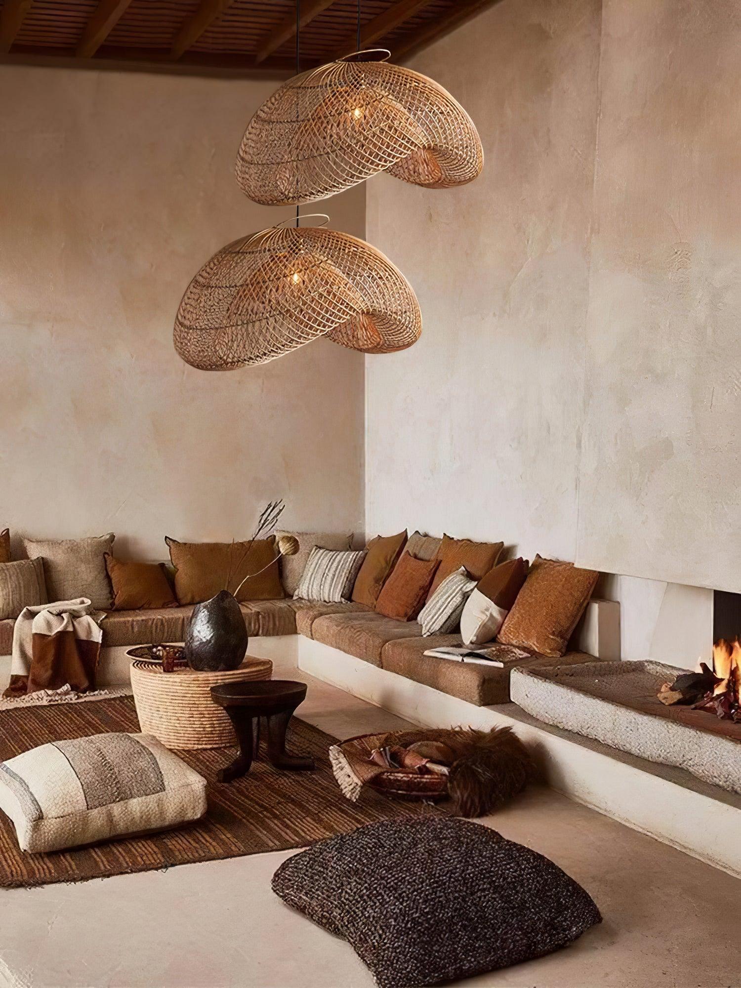 Wide living-room view with two rattan pendants, corner sofa, woven round table, floor cushions and fireplace