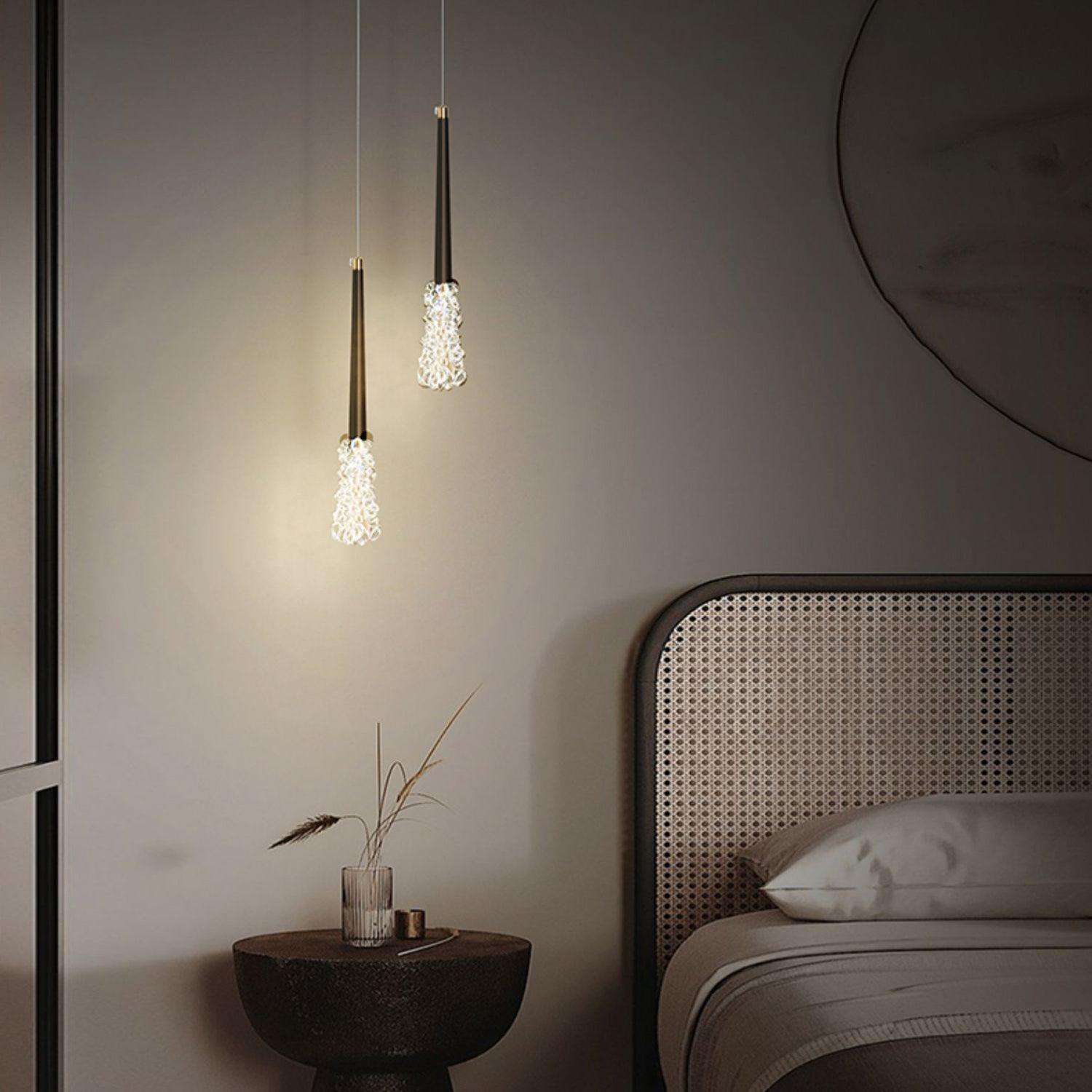 Two dark slim pendants over a bedside table