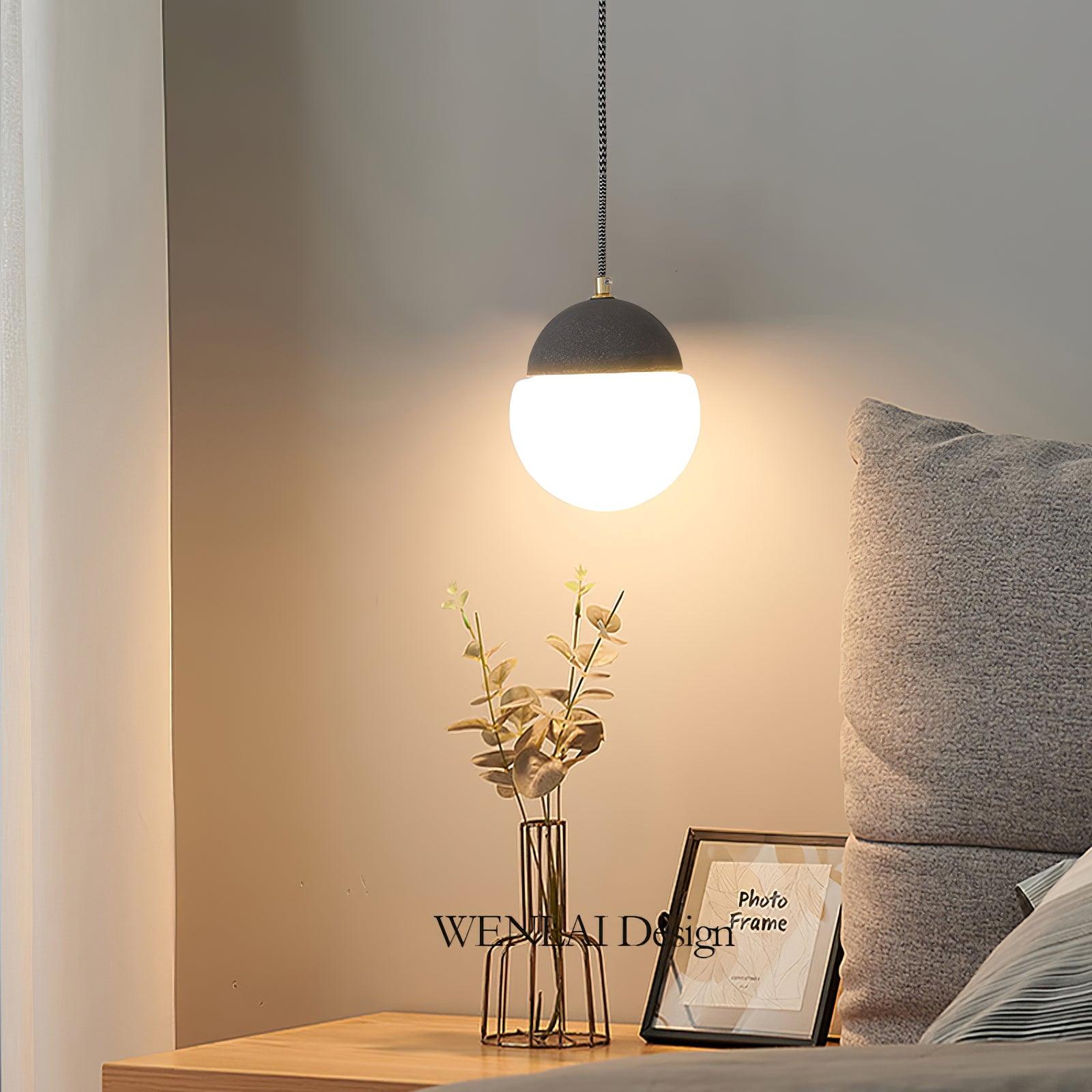 Cement Eclipse pendant beside a bed and flowers
