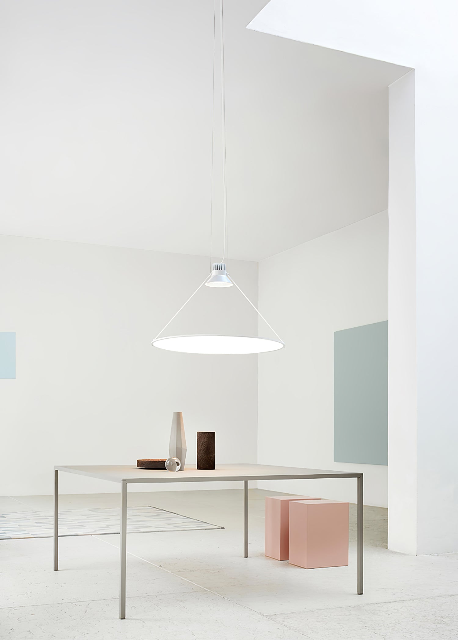 White disc pendant above a minimalist dining table