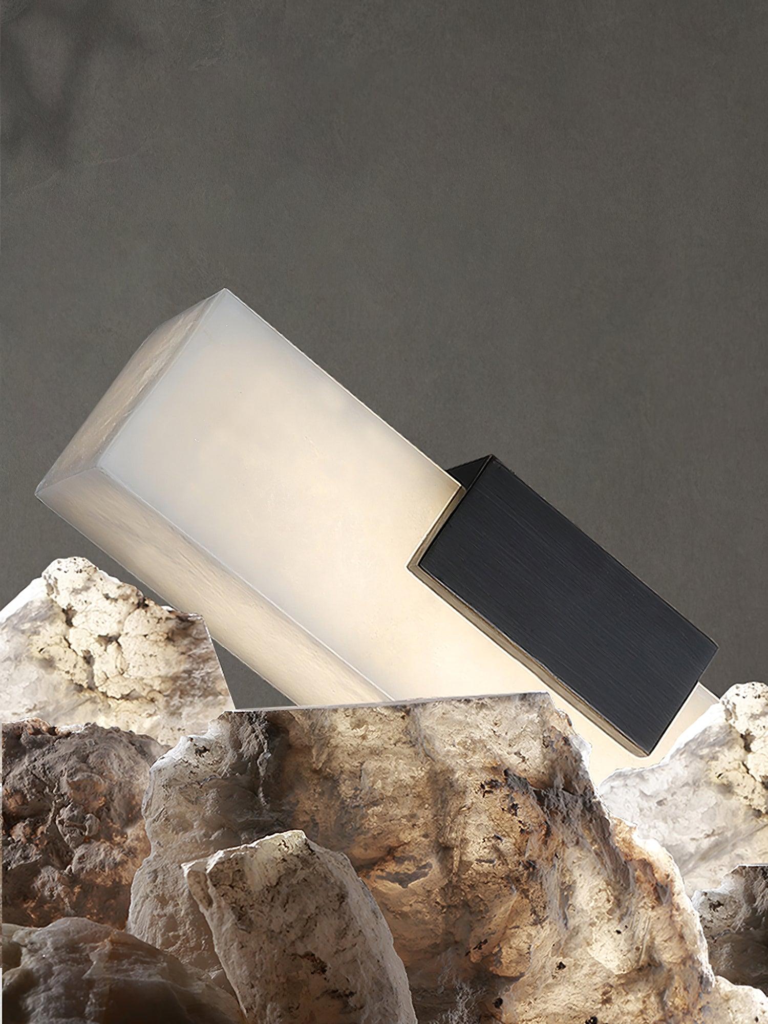 Angled glowing white pendant end with black support surrounded by stone fragments
