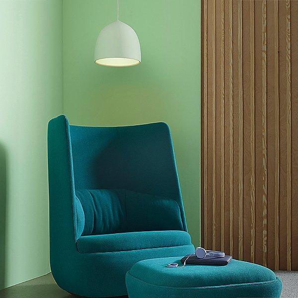 Single pale bell pendant above a green lounge chair