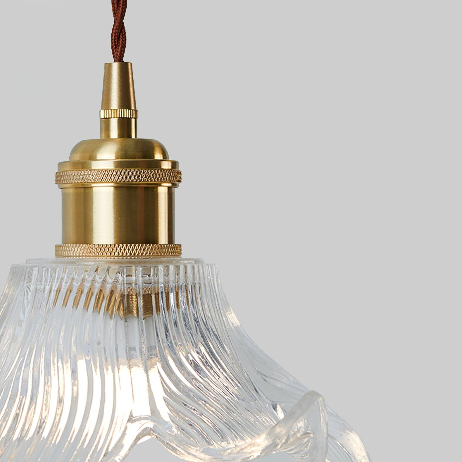Close brass-toned cylindrical holder, domed cap, knurled bands and conical cable entry beneath a twisted brown cord.