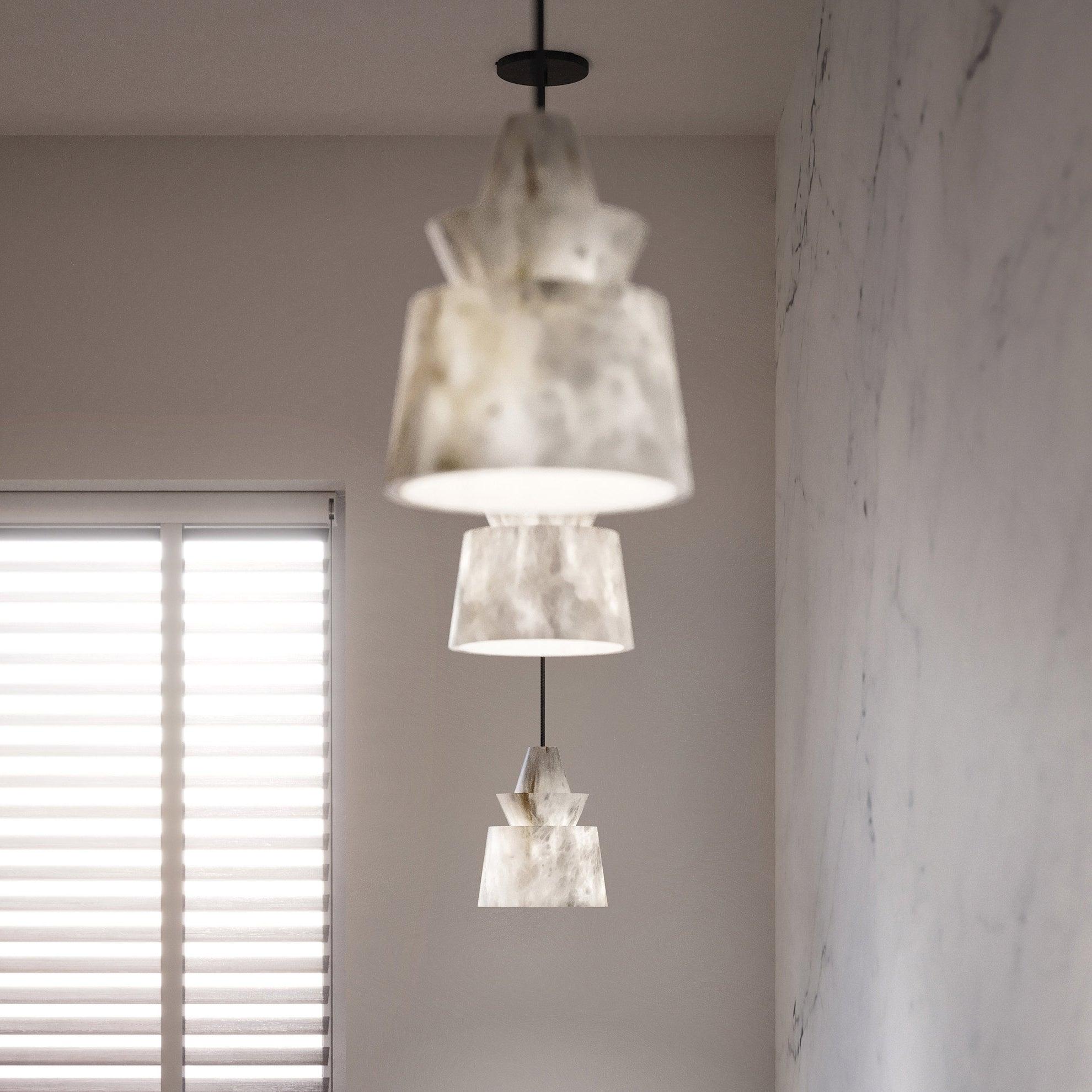Depth view of three broad-bottom alabaster pendants, nearest blurred, with black canopy, window blinds and veined wall.