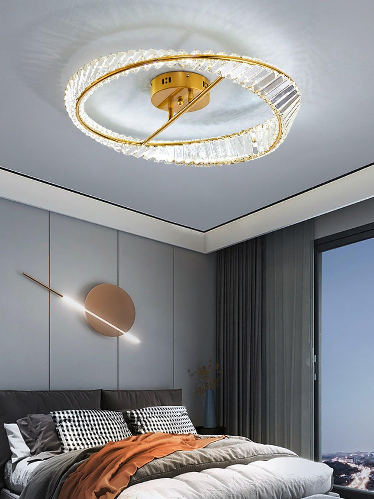 Bright glass ring ceiling light above a bed with an orange throw and a round wall light