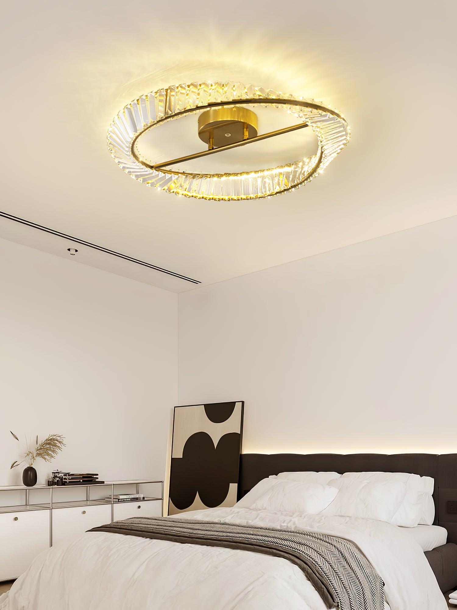 Ring ceiling light above a white bed with a black headboard and leaning geometric artwork