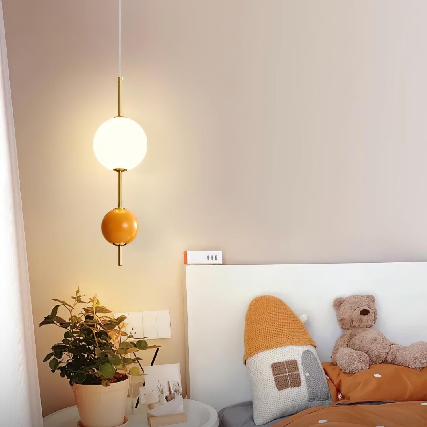 Orange two-ball pendant near a bed and plant