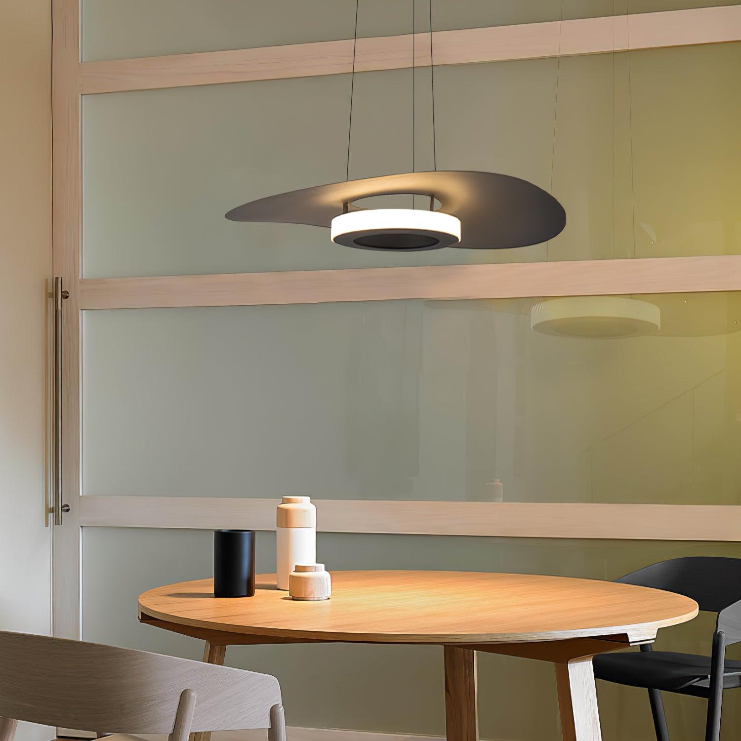 Dark disc pendant above round wooden table with three vessels before green glazed sliding partition