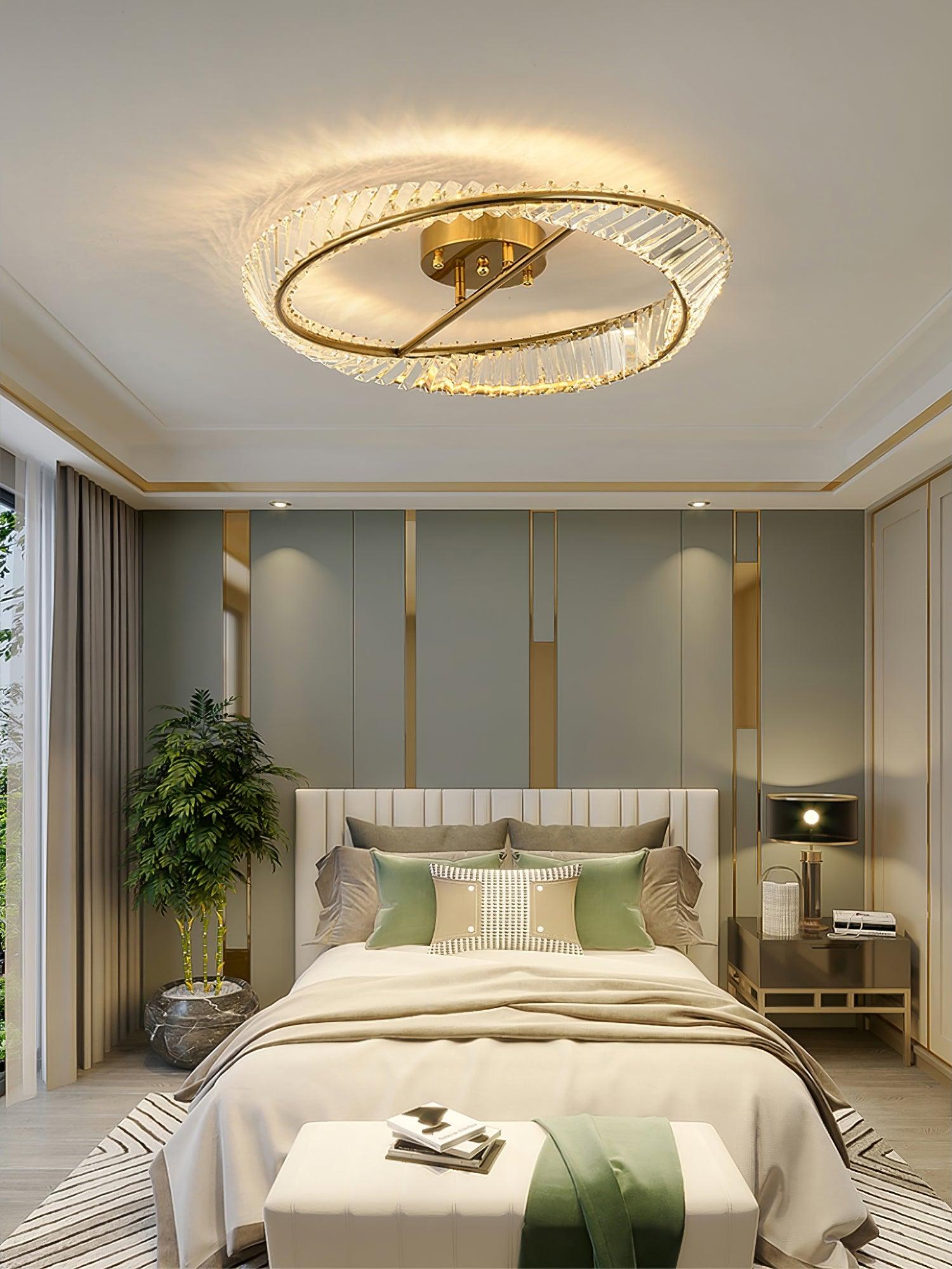 Illuminated ring ceiling light above a bed with green cushions and a black bedside lamp
