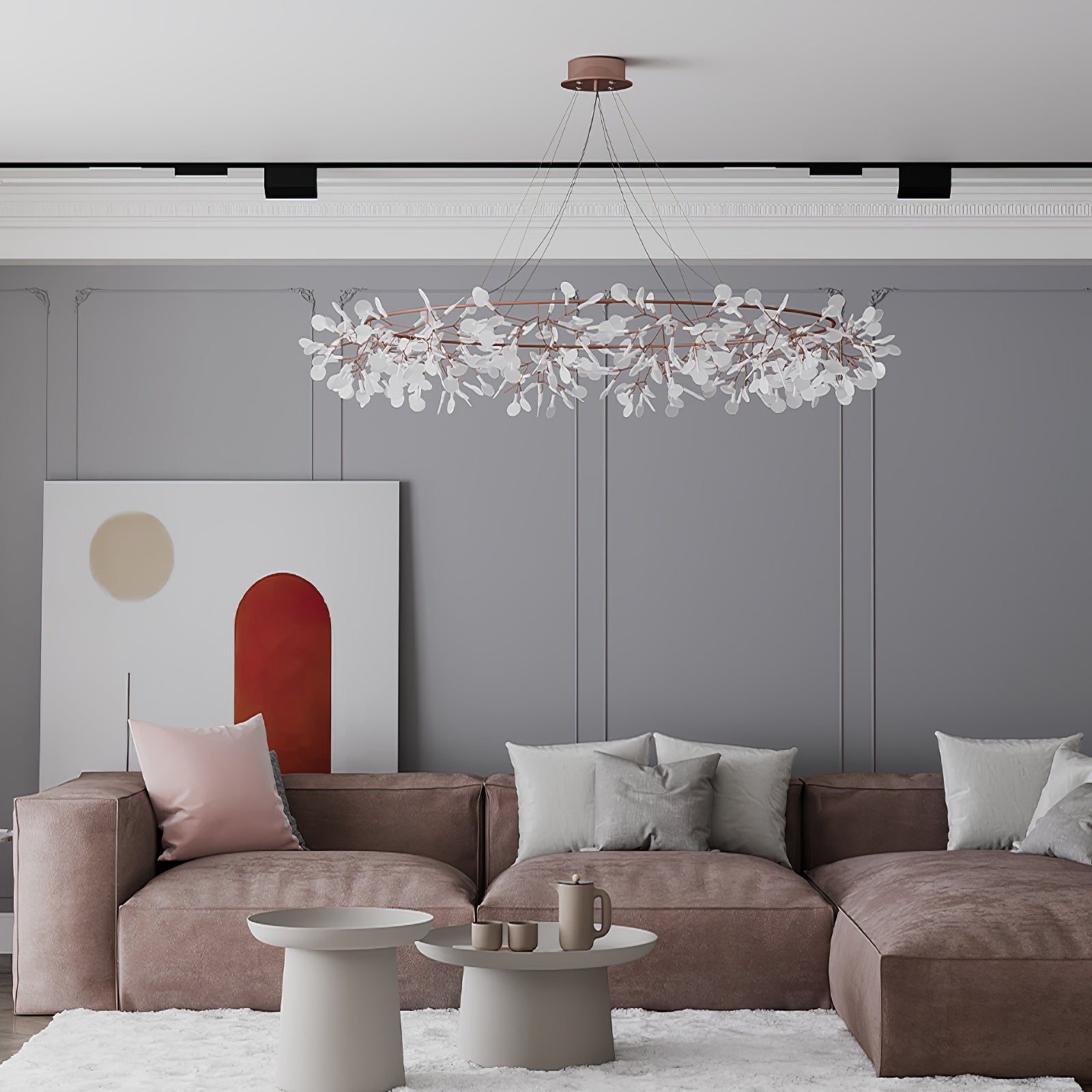 Closer view of a rose-copper leaf ring chandelier above a taupe sofa beneath grey wall mouldings