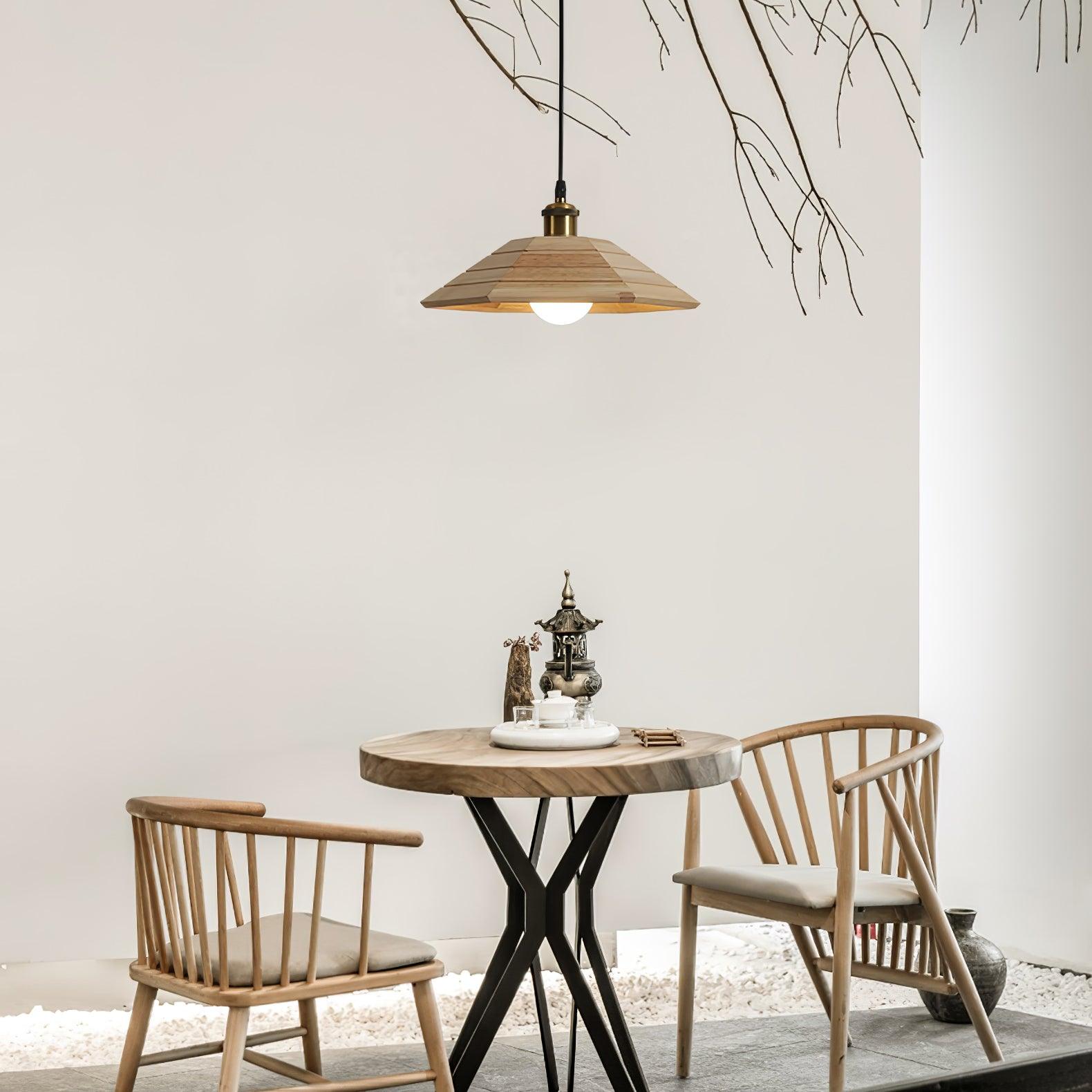 Light wood umbrella pendant above a round tea table with teaware, two wooden chairs and bare branches