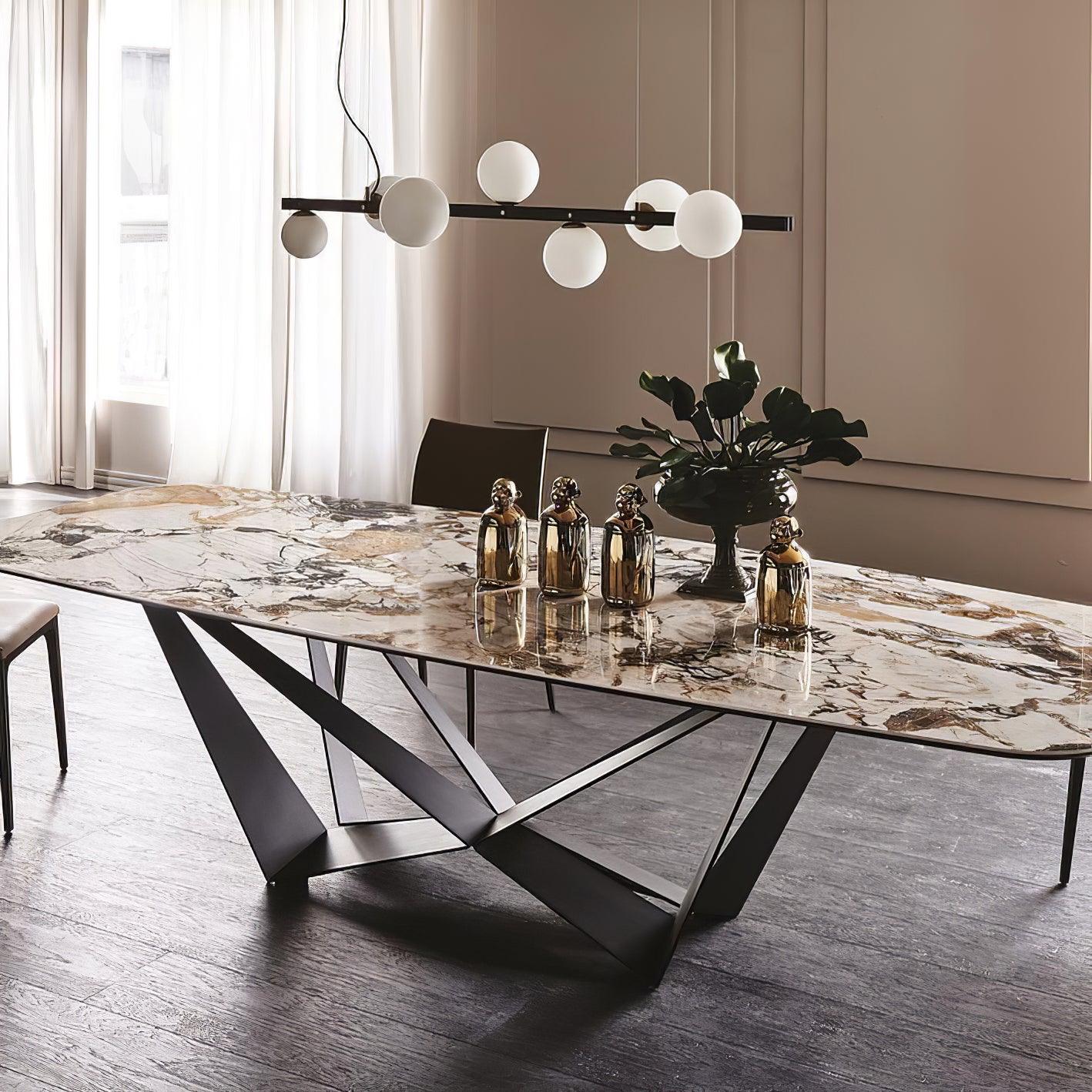 Unlit globe pendant above a veined marble table with gold-tone bottles, leafy vase and angular black base by sheer curtains.
