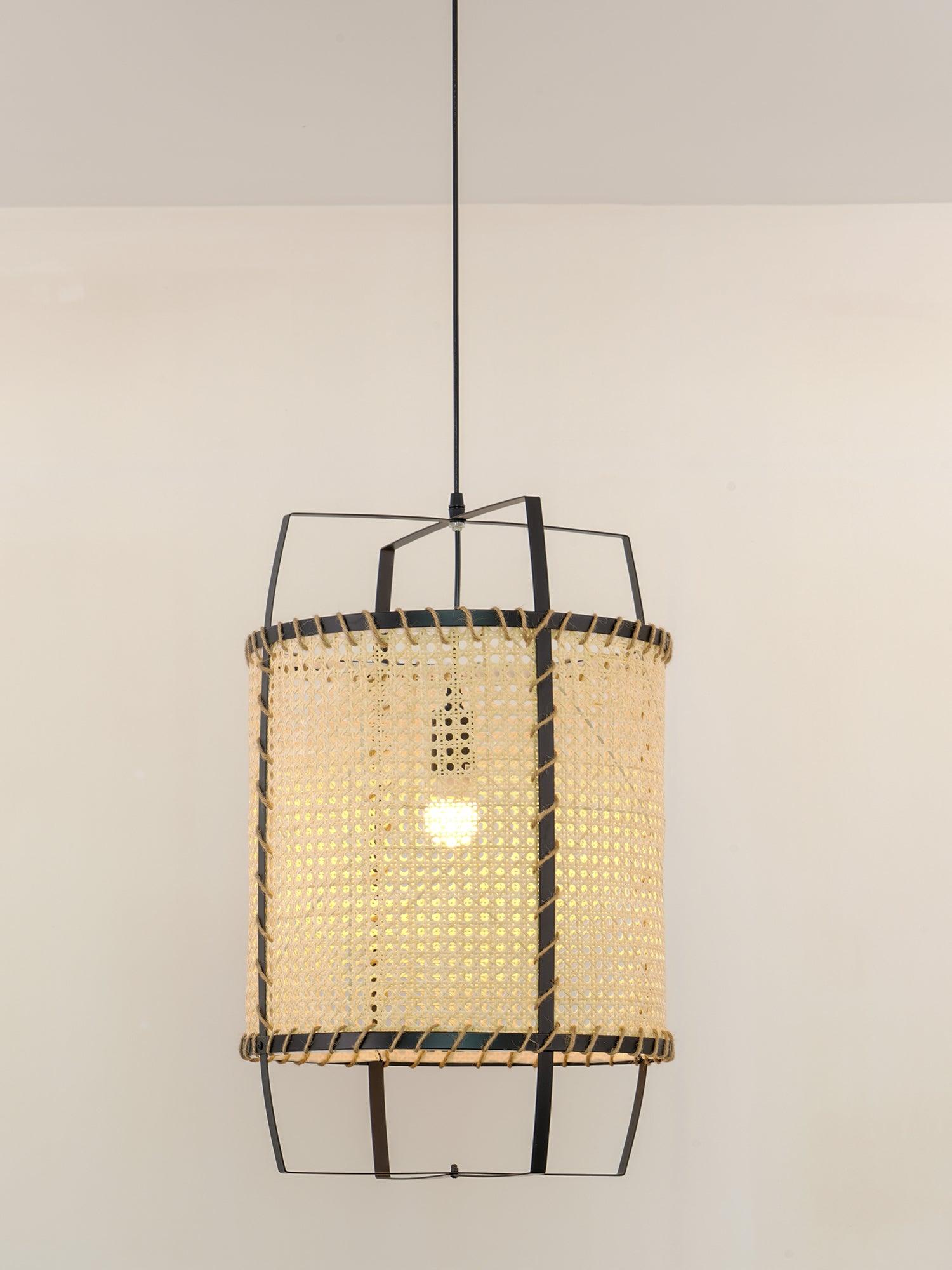 Lit cane pendant with a visible glowing bulb, black rims and geometric frame against a pale background