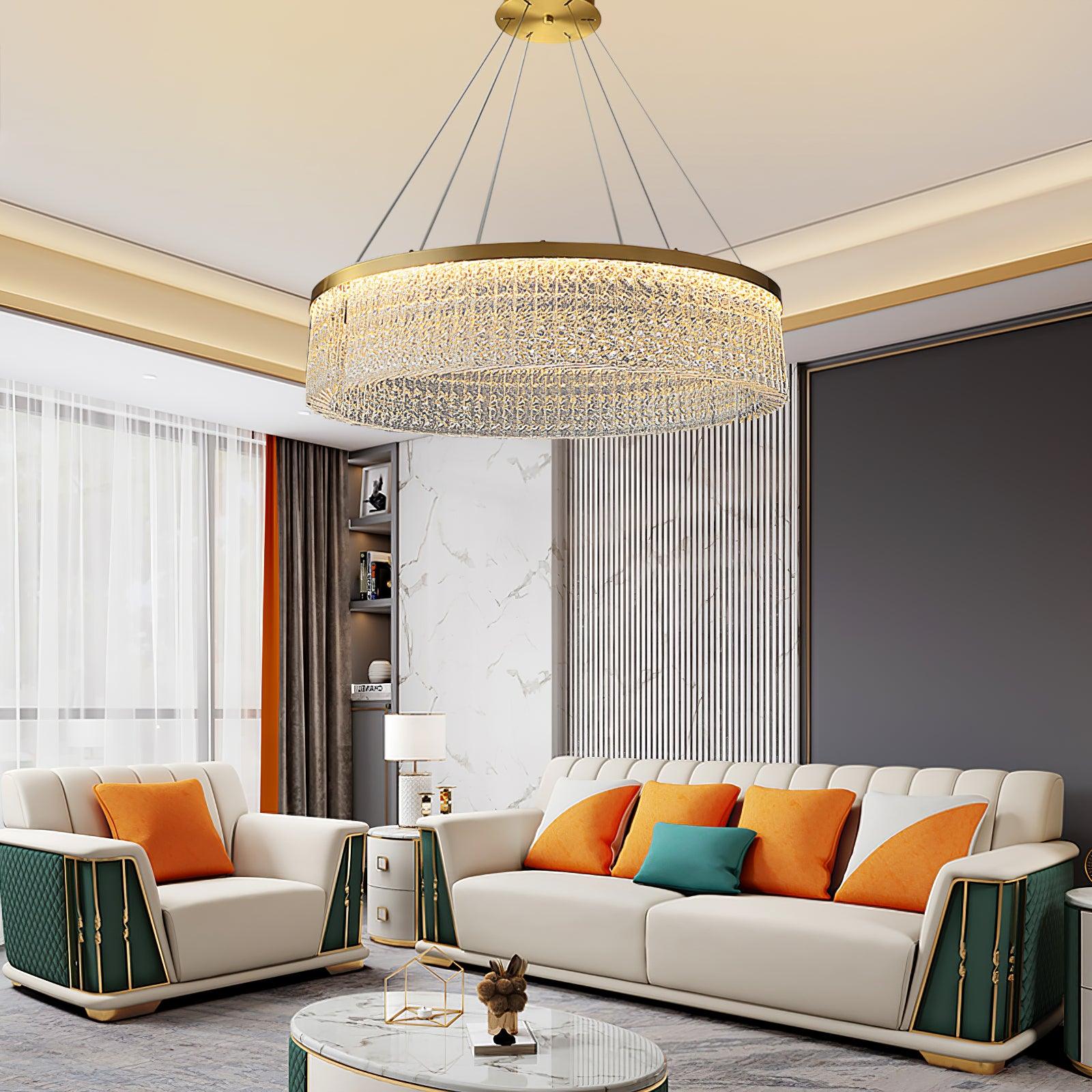 Illuminated crystal ring above white and green seating with orange cushions, oval stone-pattern table and ribbed wall