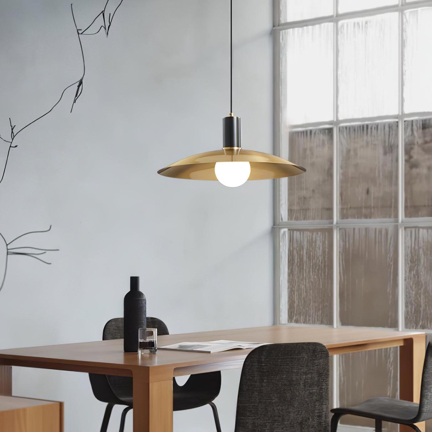 Single brass-shade pendant above a dining table