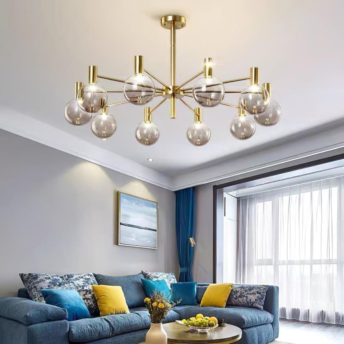 Clear-globe chandelier above a blue sectional with yellow cushions and a fruit bowl, beside blue curtains and white sheers.