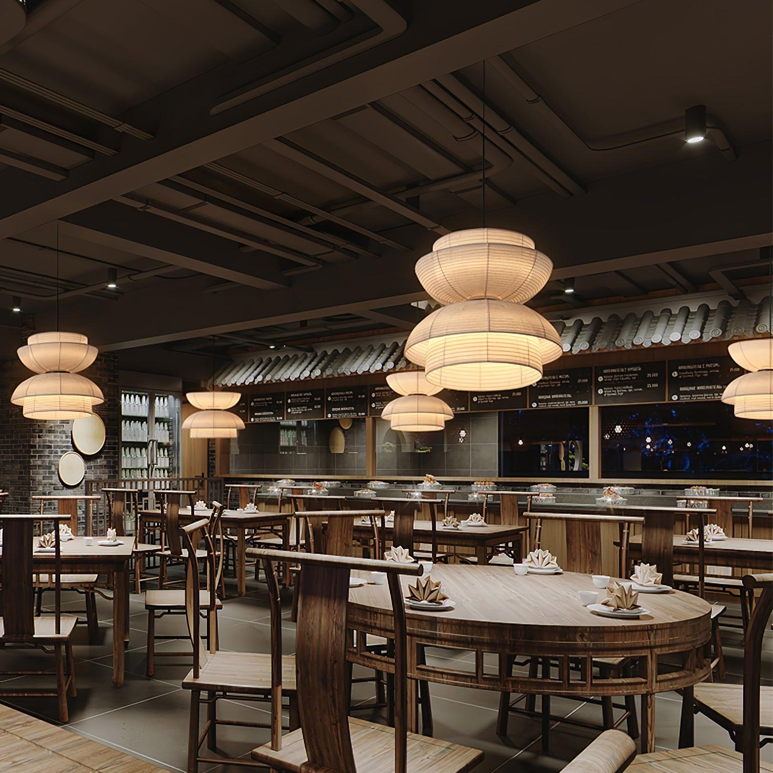 Facing-bowl fabric pendants above wood restaurant tables and chairs, with dark ceiling and decorative tile edging