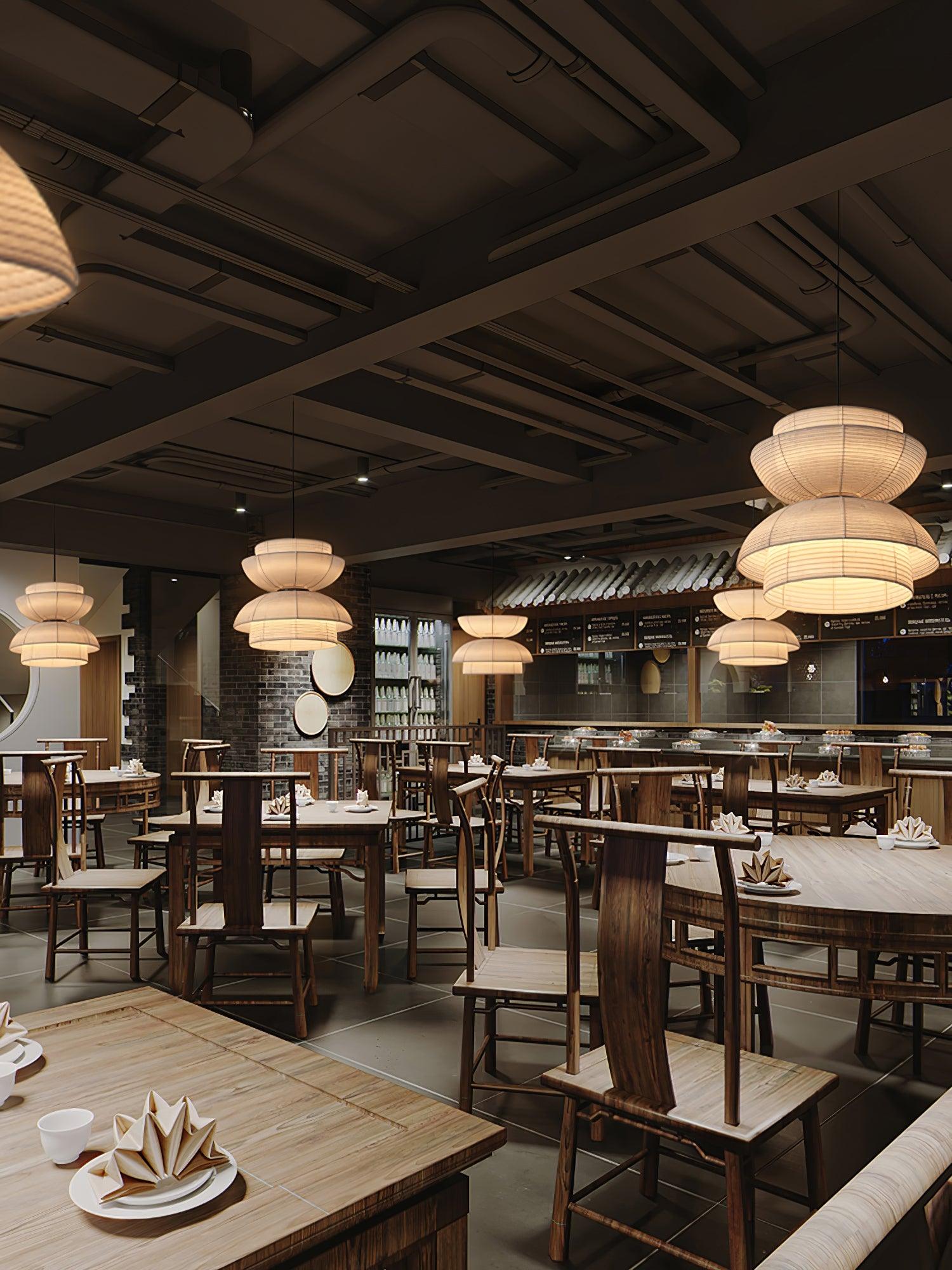 Portrait restaurant view with separate facing-bowl pendants above wooden dining tables, chairs and a menu wall
