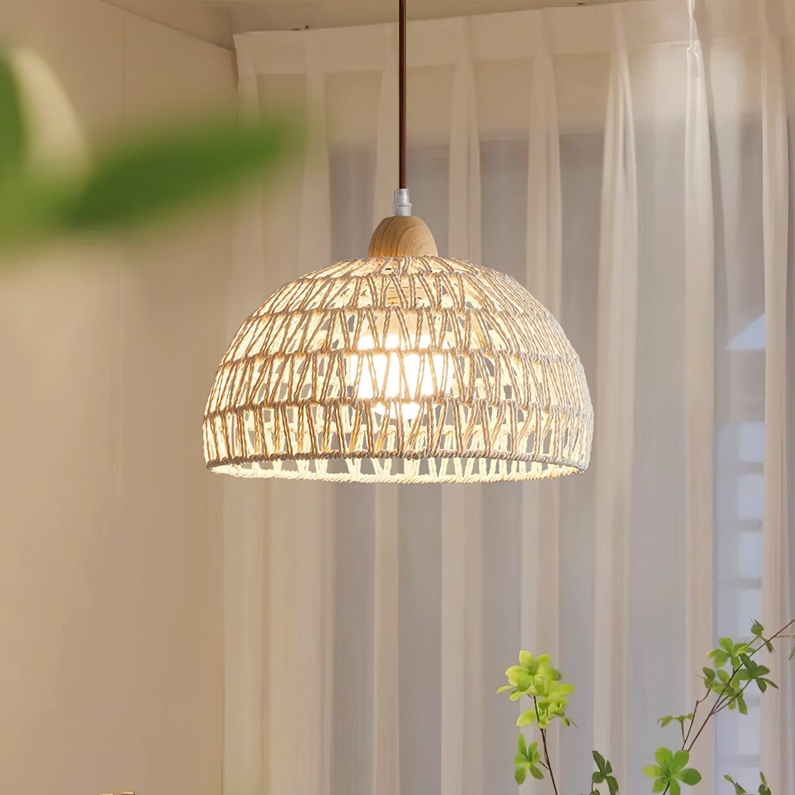 Close view of a lit open-weave dome and wood-grain cap before white curtains and green foliage