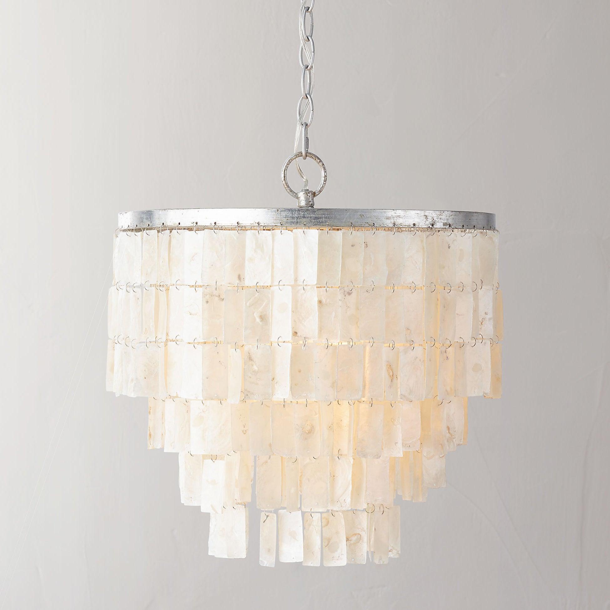 Pale rectangular shell tiles cascading below a silver top ring, with chain and translucent wire against a light wall