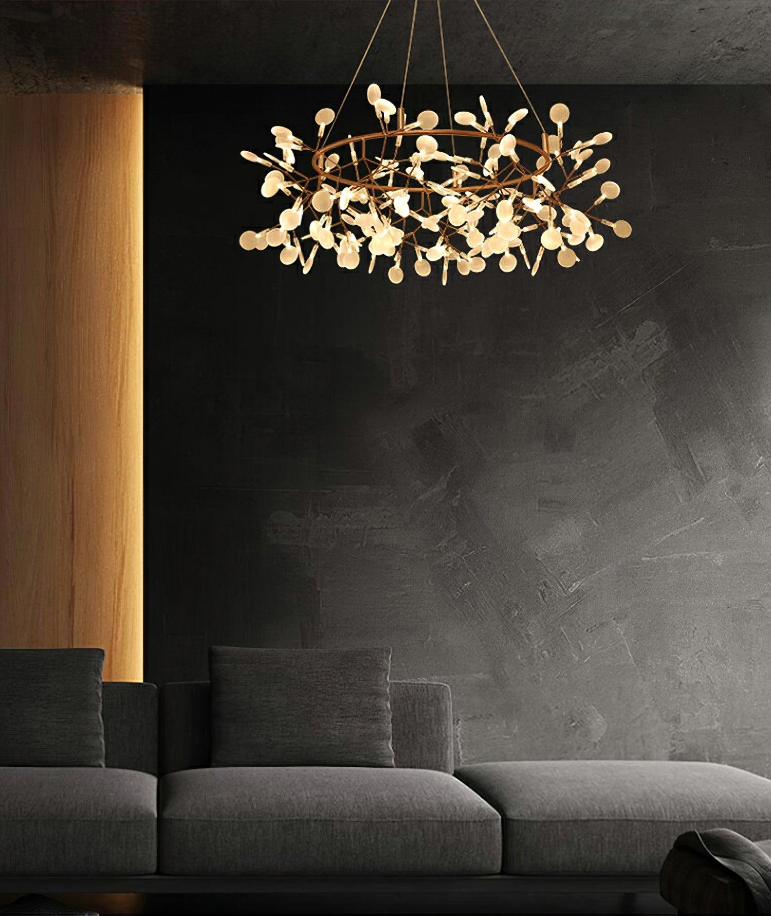 Warm metallic leaf ring chandelier above a charcoal sofa against a dark textured wall and timber panel