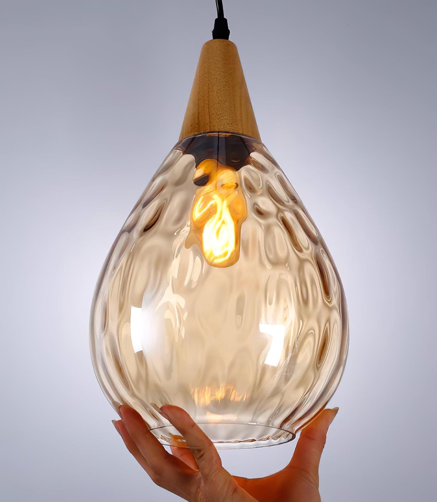 Amber teardrop glass pendant held for a close view