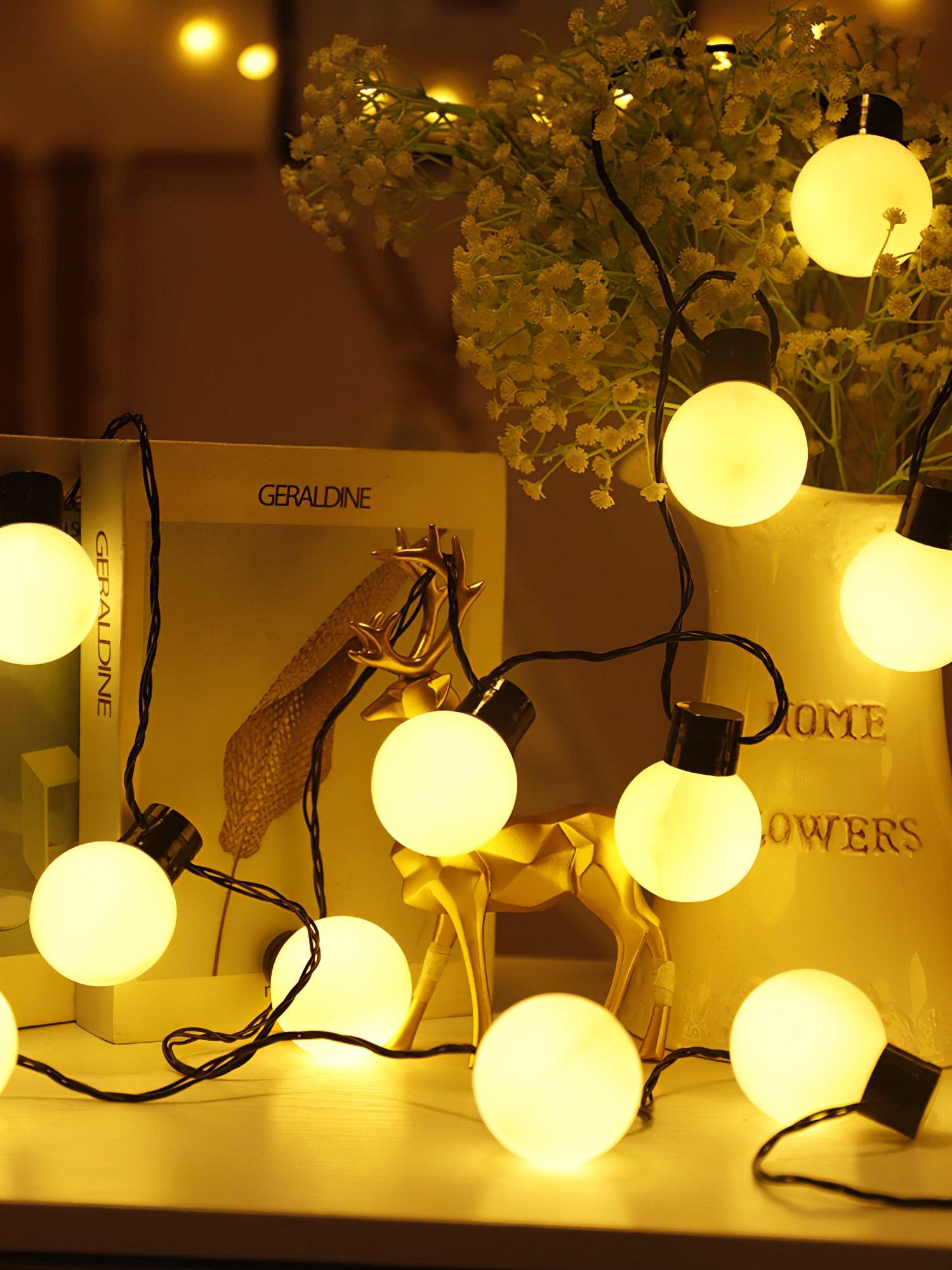 Globe string lights arranged near flowers on a table