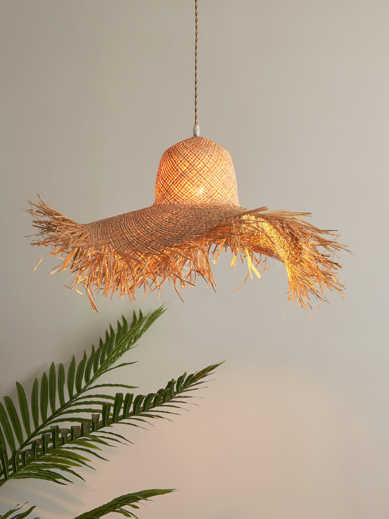 Close glowing rattan hat shade with wavy fringed brim, pale cord connector and palm leaves below left